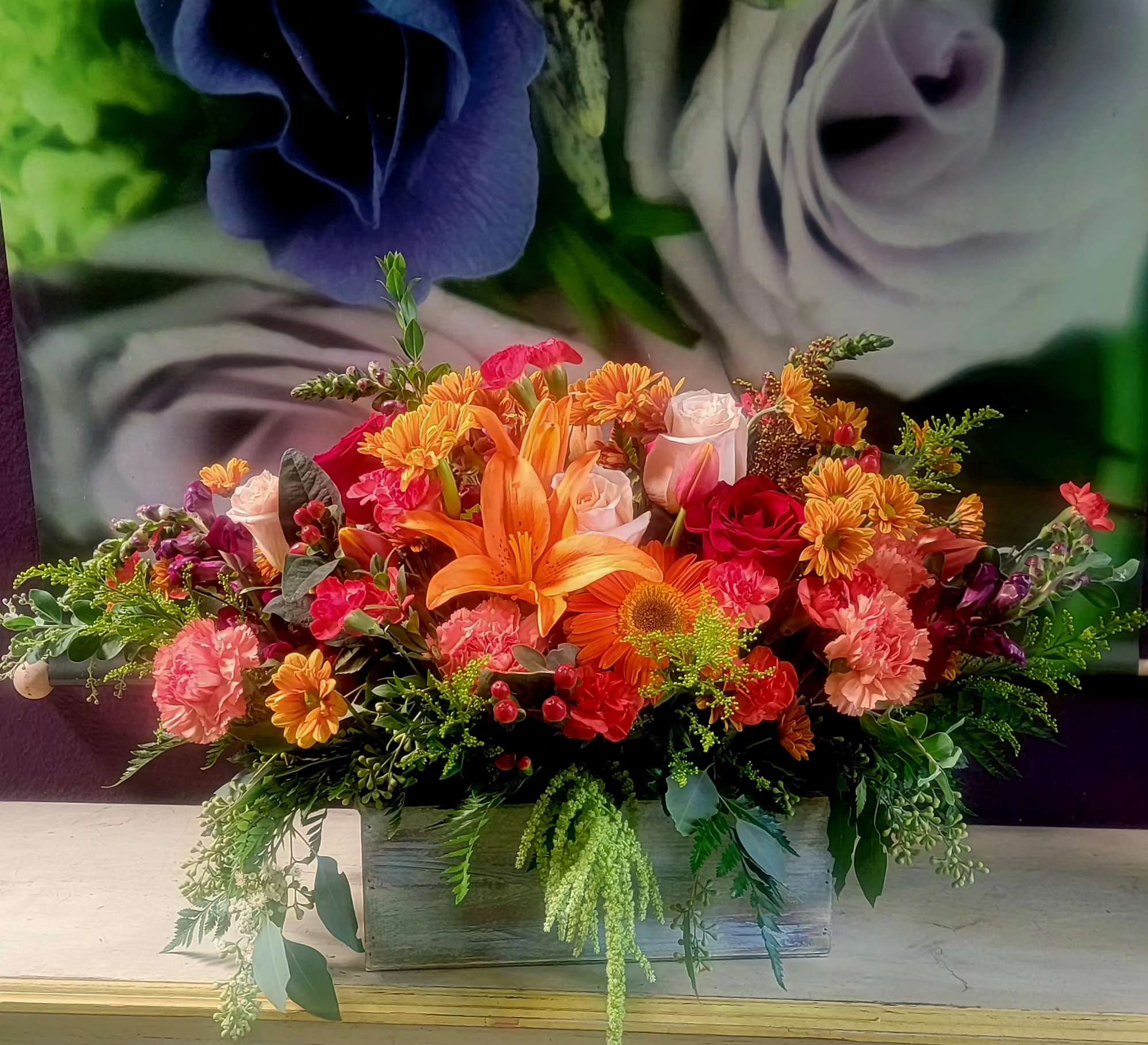 Colorful floral arrangement with lilies, roses, and mums in a wooden box