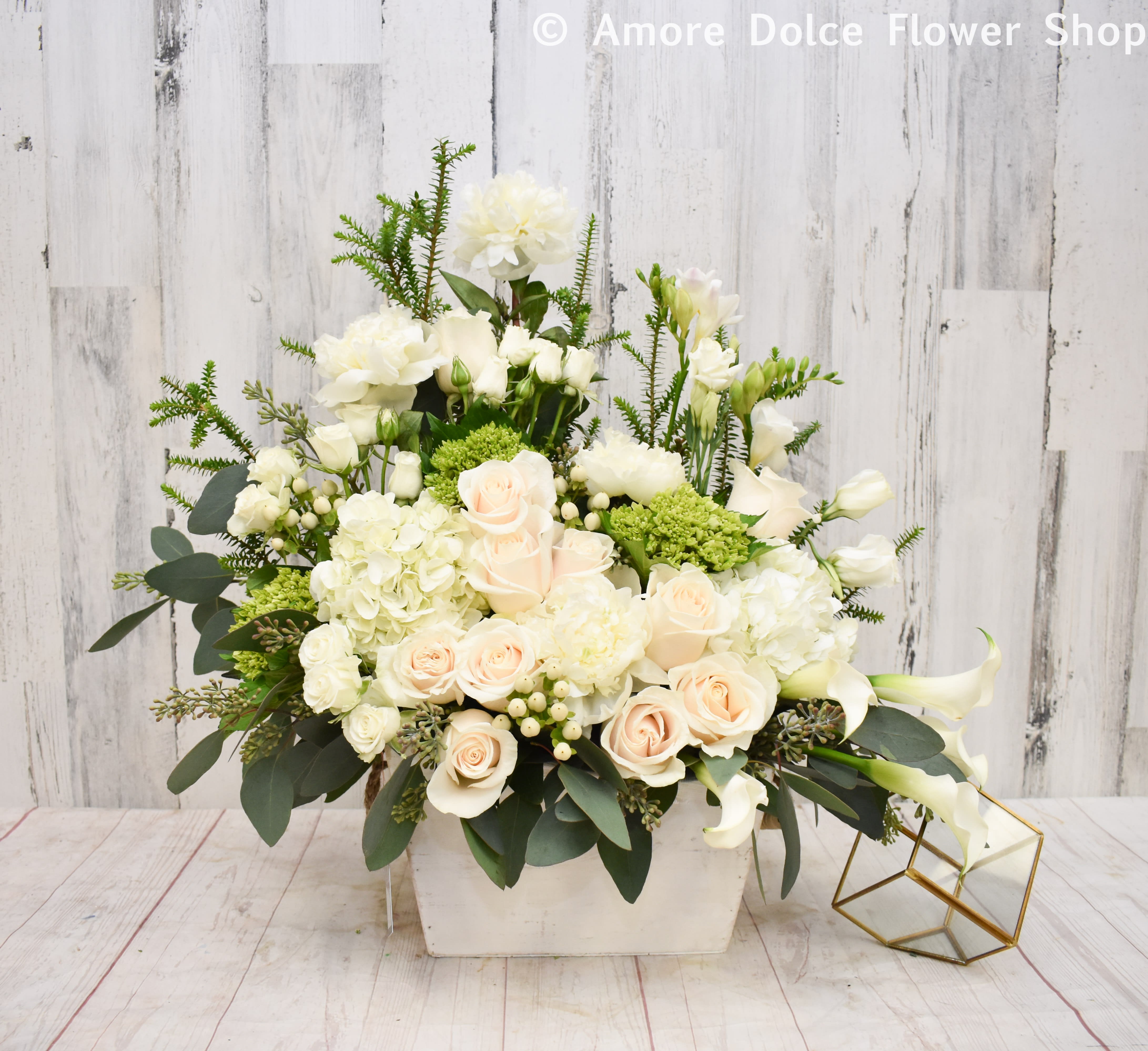 White and blush floral arrangement in a rectangular vase with calla lilies and roses