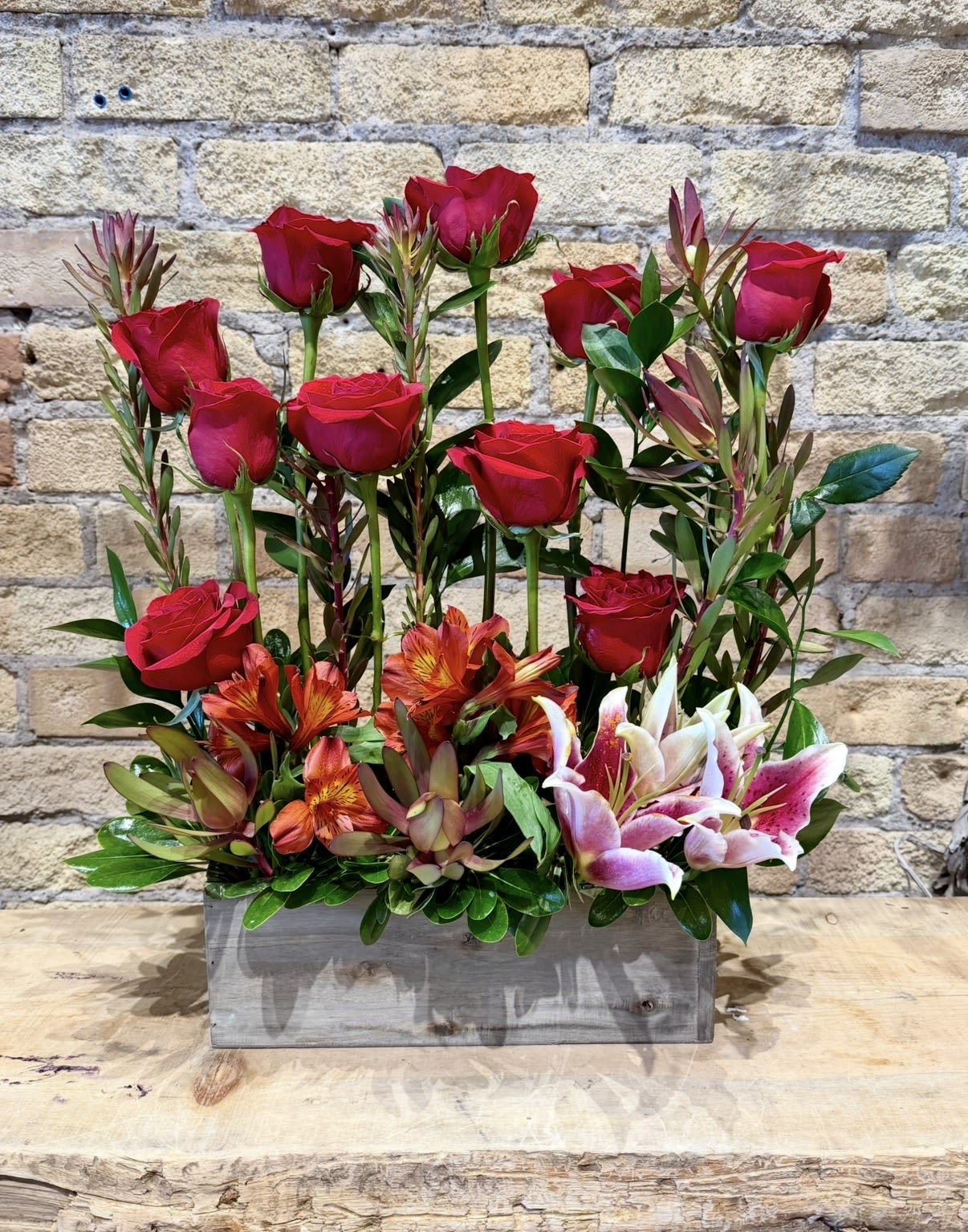 Red roses and pink lilies arranged in a wooden box