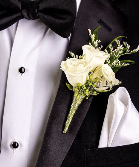 White rose boutonniere pinned to a black tuxedo jacket