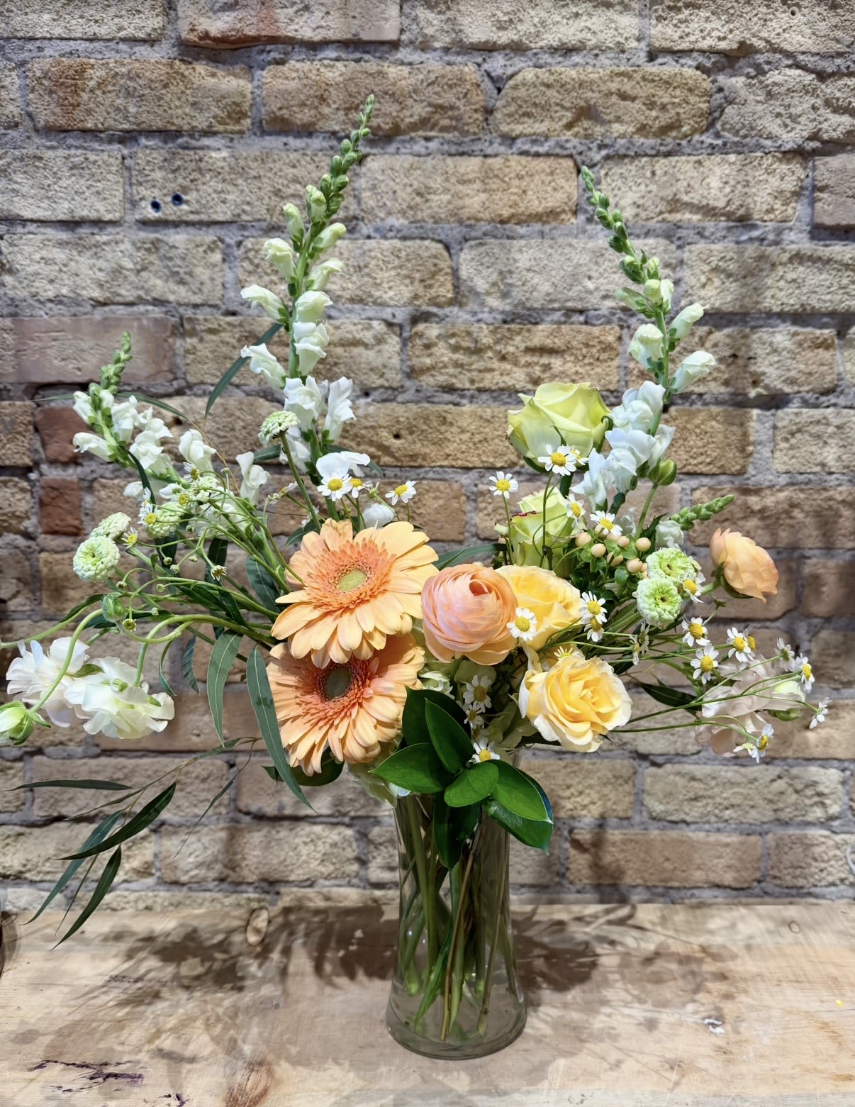 Peach and yellow mixed bouquet in a clear glass vase