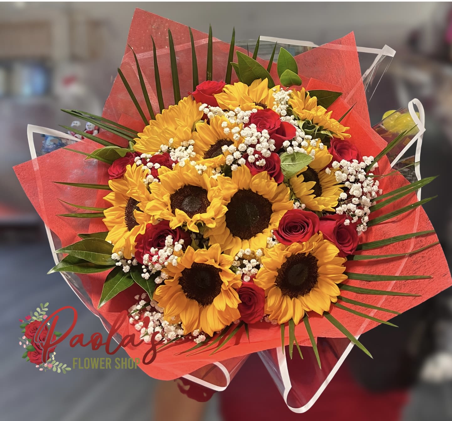 Bouquet of sunflowers and red roses wrapped in red paper