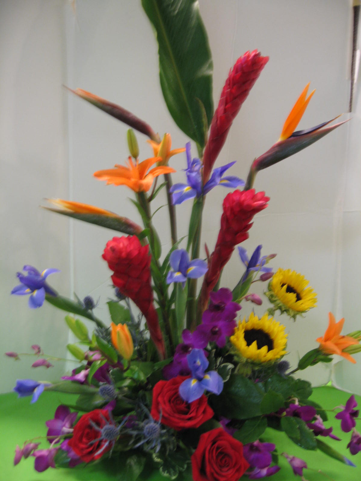 Tall tropical bouquet with red roses, sunflowers, and purple flowers