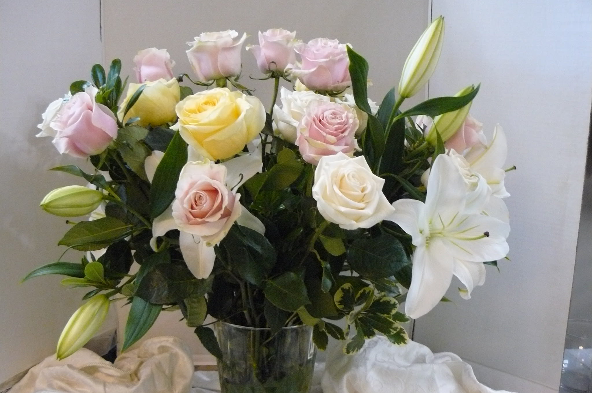 Bouquet of pink and white roses with white lilies in a glass vase
