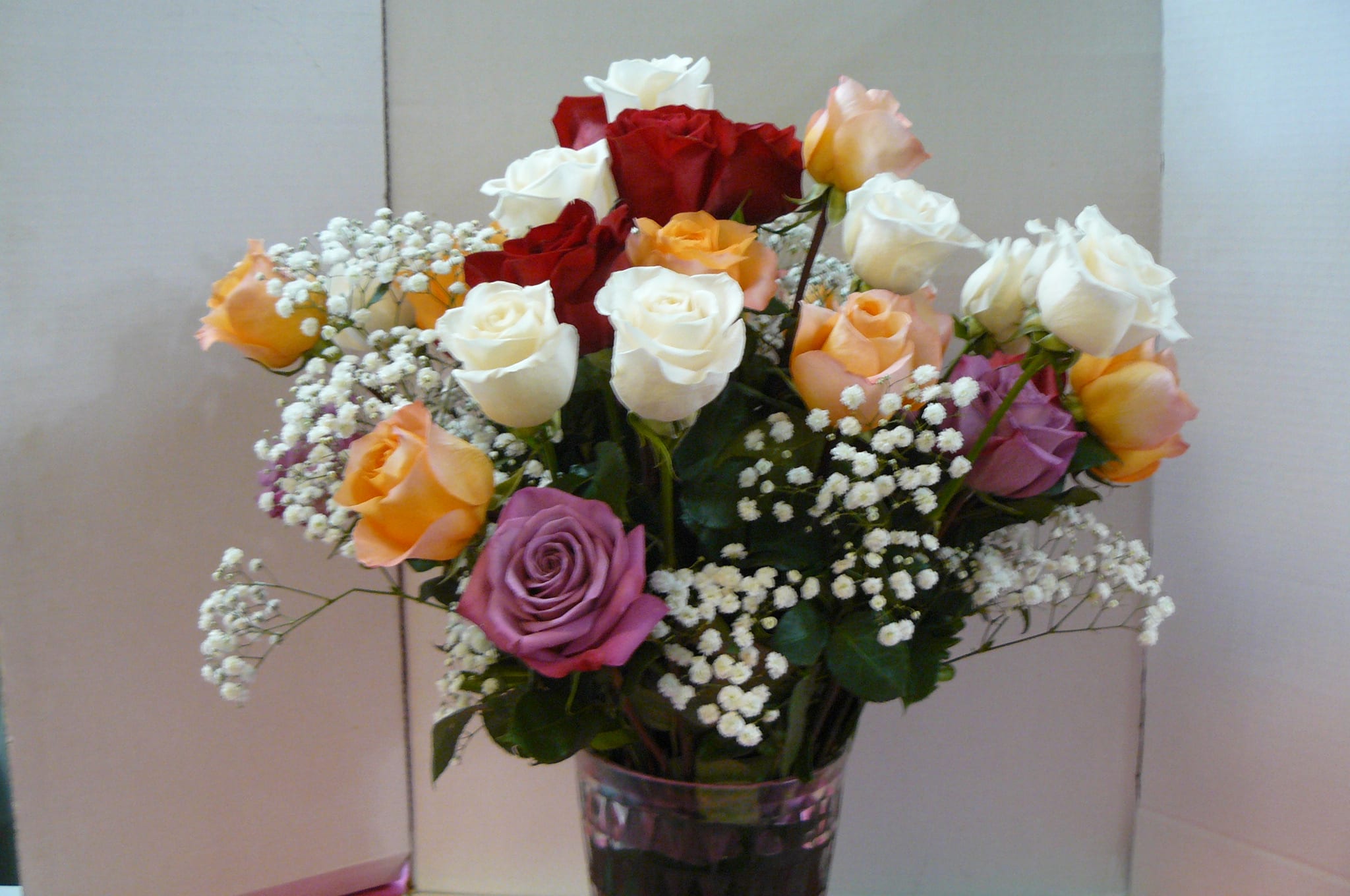 Mixed roses in a clear glass vase with baby's breath