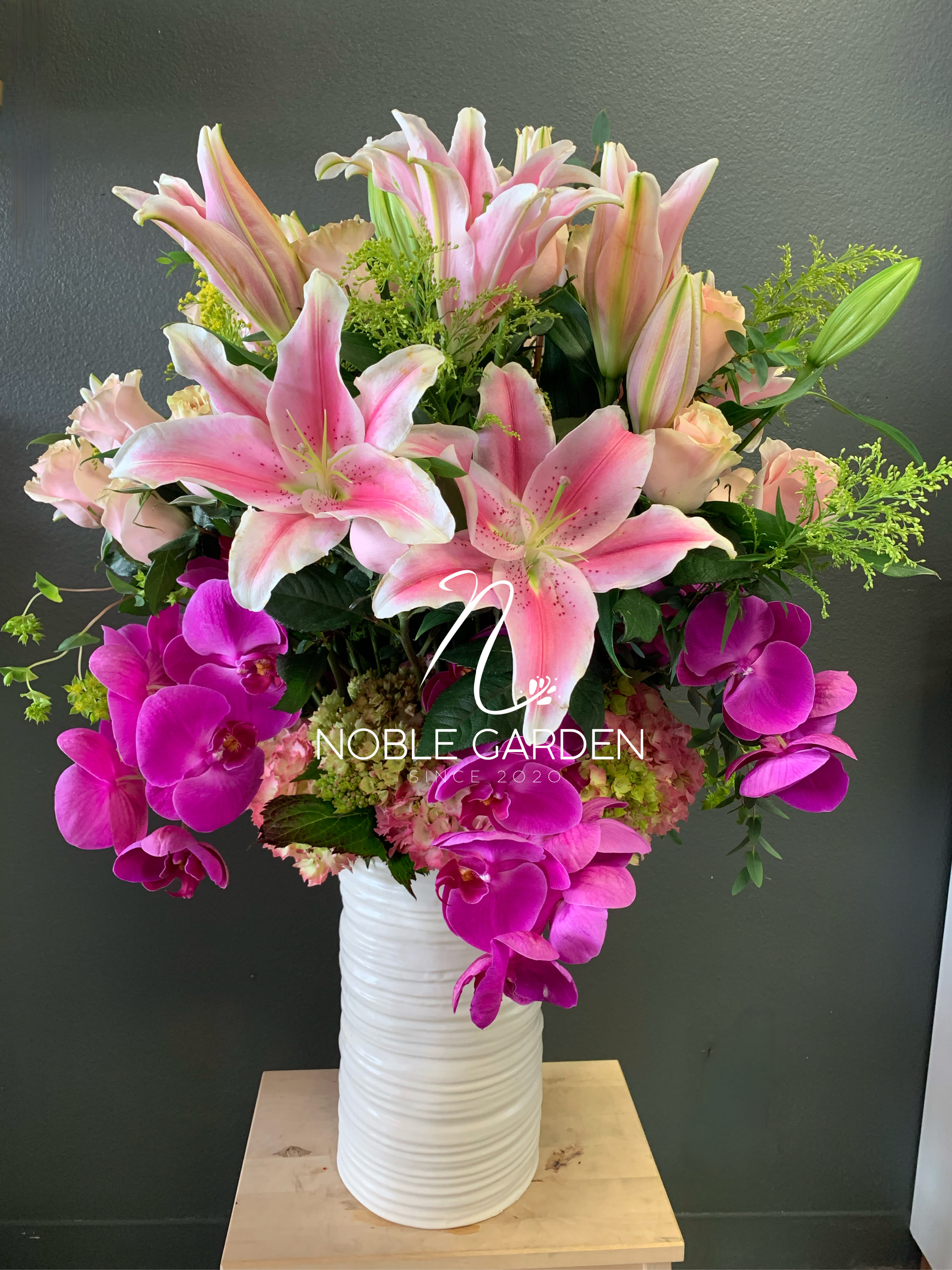 Pink lilies and magenta orchids in a white vase
