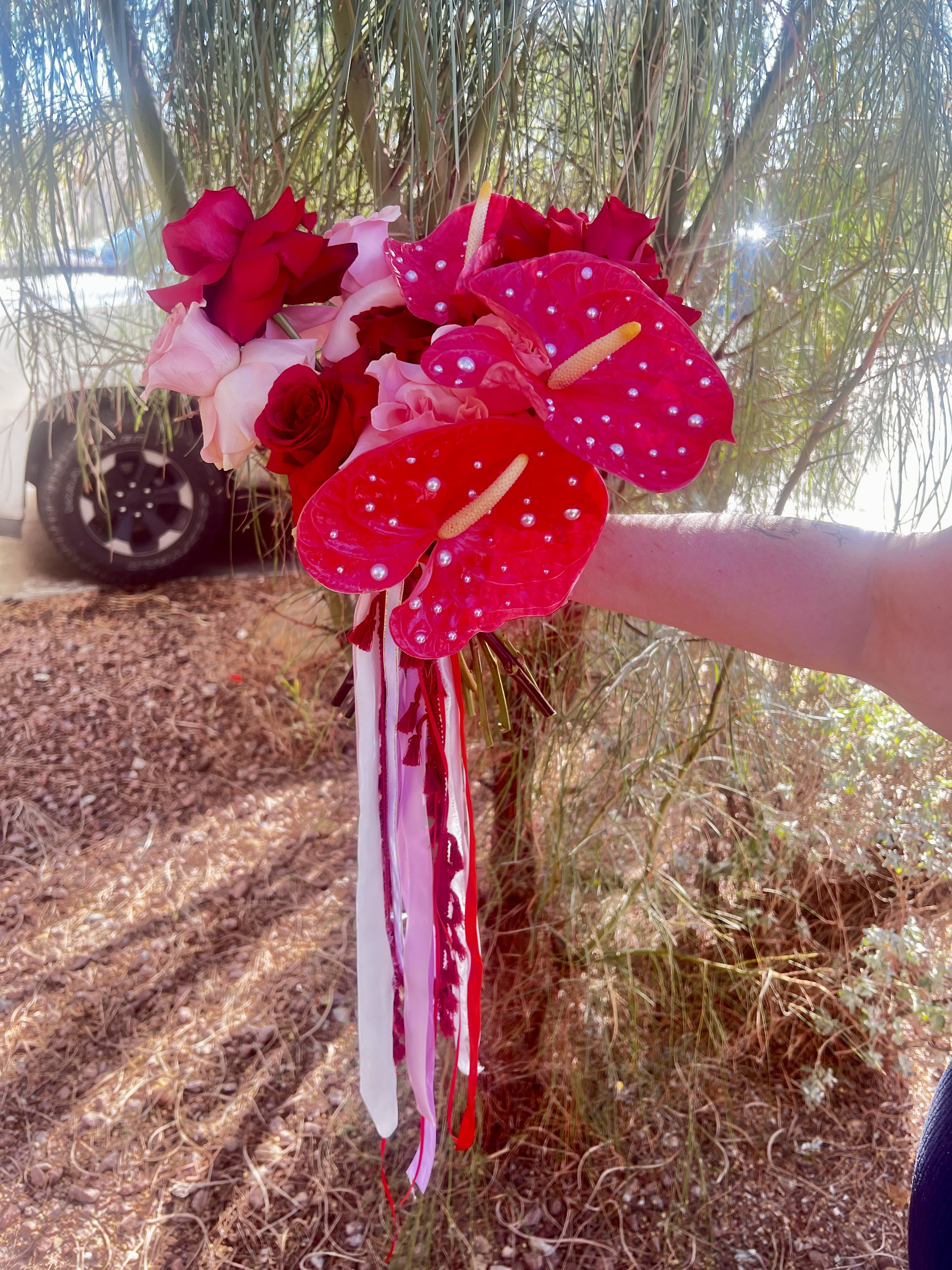 Handheld bouquet of red and pink roses with bright pink anthuriums