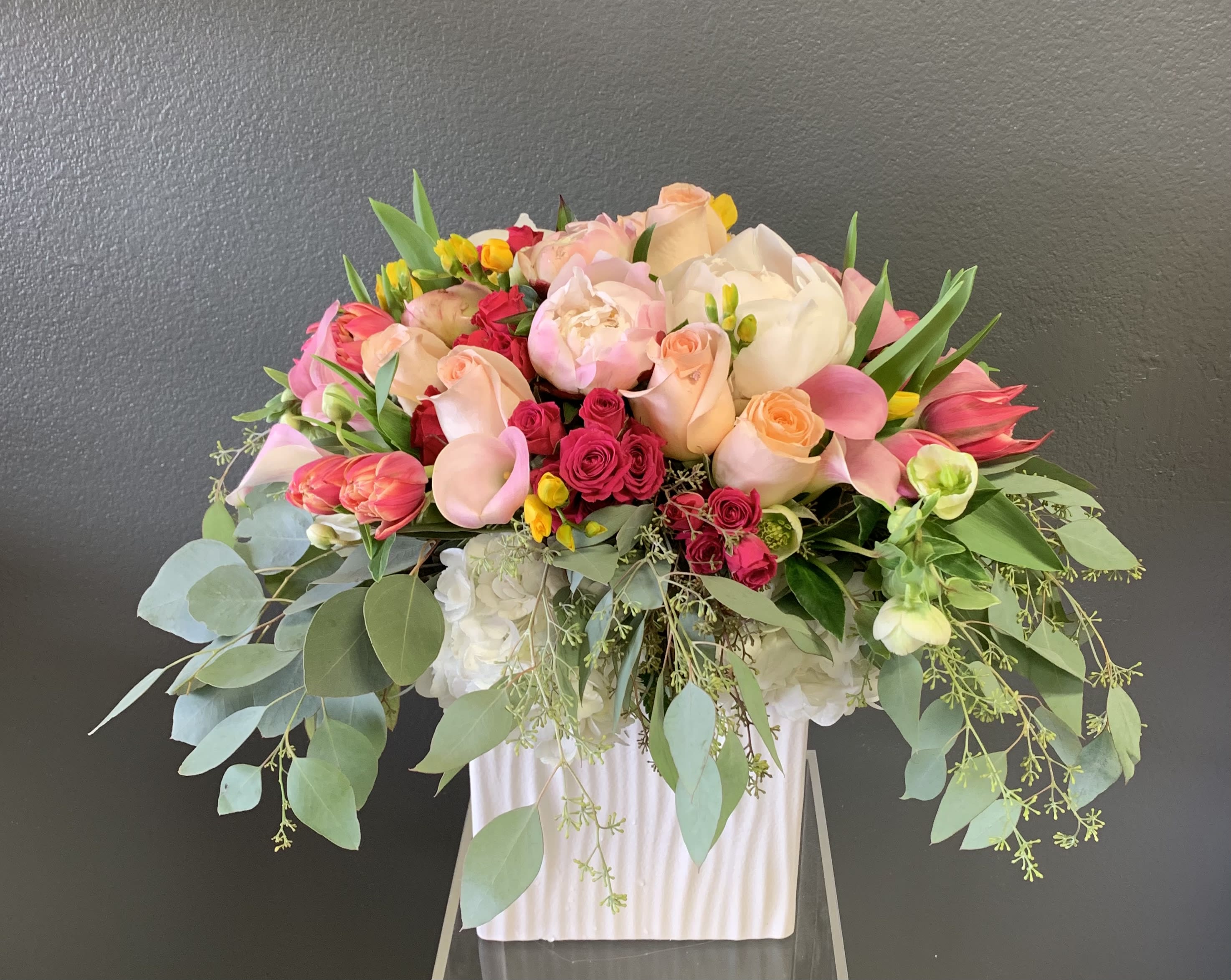 Large bouquet of pink and peach roses with white blooms in a white vase