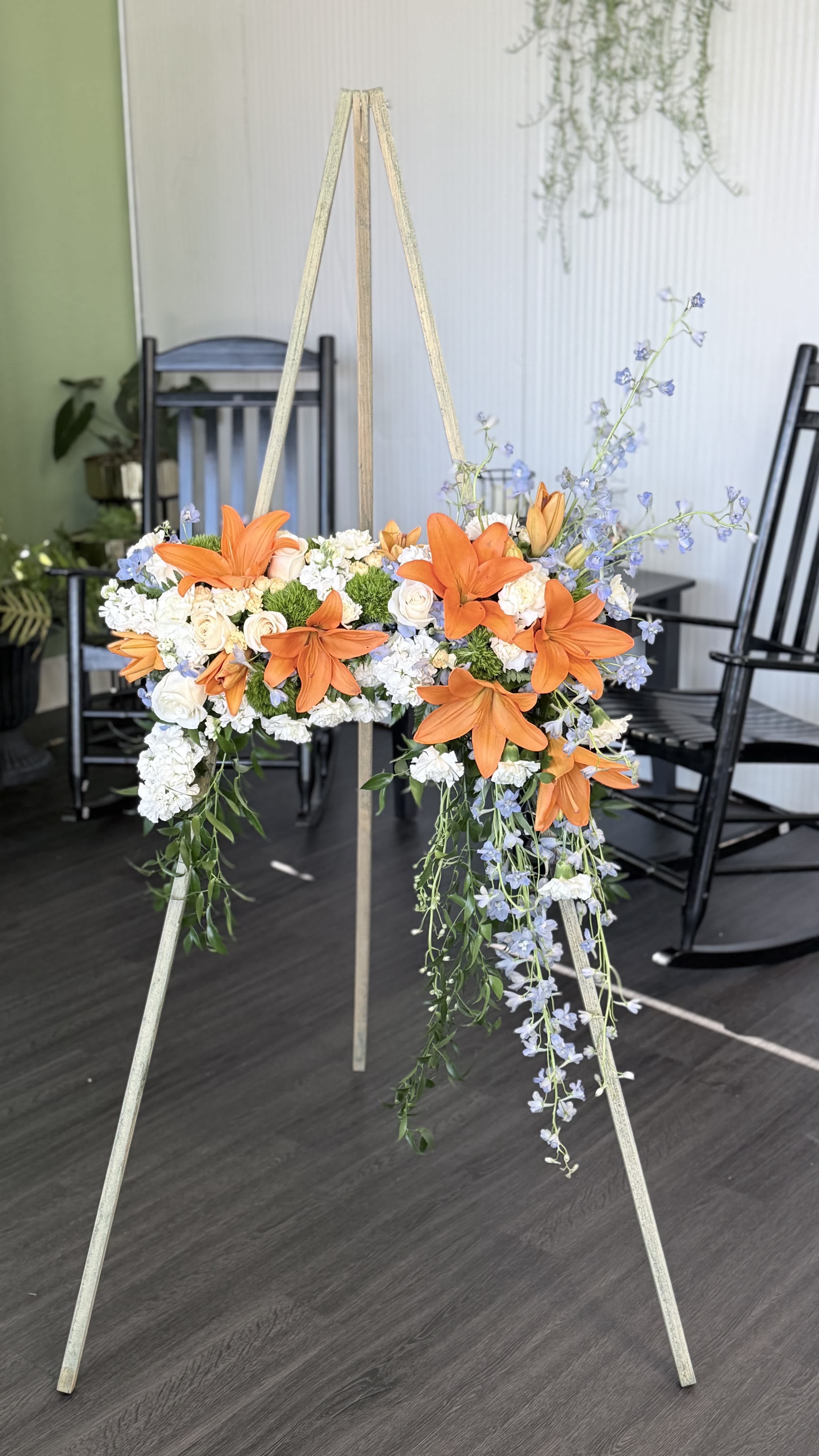 Orange lilies and white flowers arranged on a standing easel
