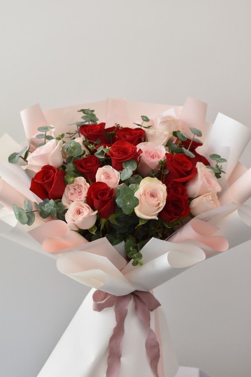 Bouquet of red and pale pink roses wrapped in white paper