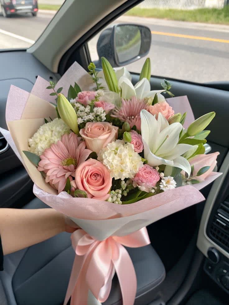 Pink and white bouquet with roses, lilies, and gerbera daisies wrapped in pastel paper