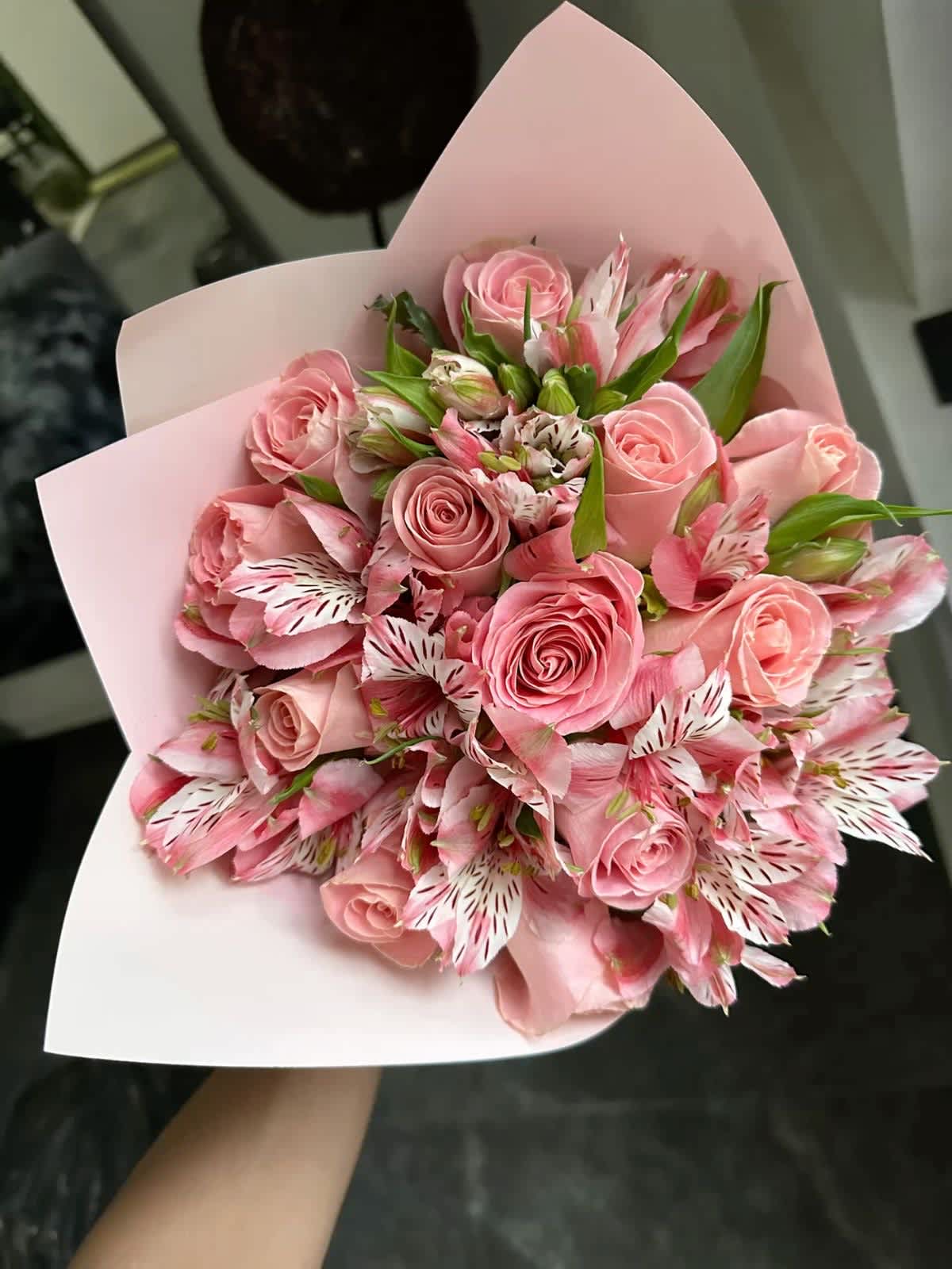Pink rose bouquet with striped pink-and-white alstroemeria in pale wrapping