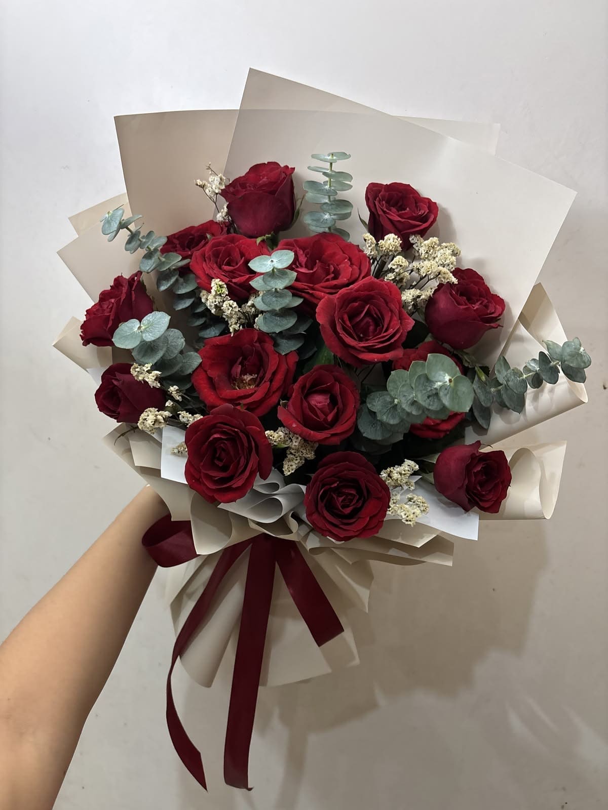 Bouquet of red roses with eucalyptus and cream filler, wrapped in beige paper