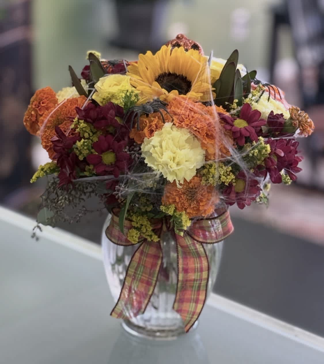 Mixed bouquet with a sunflower in a glass vase and plaid ribbon