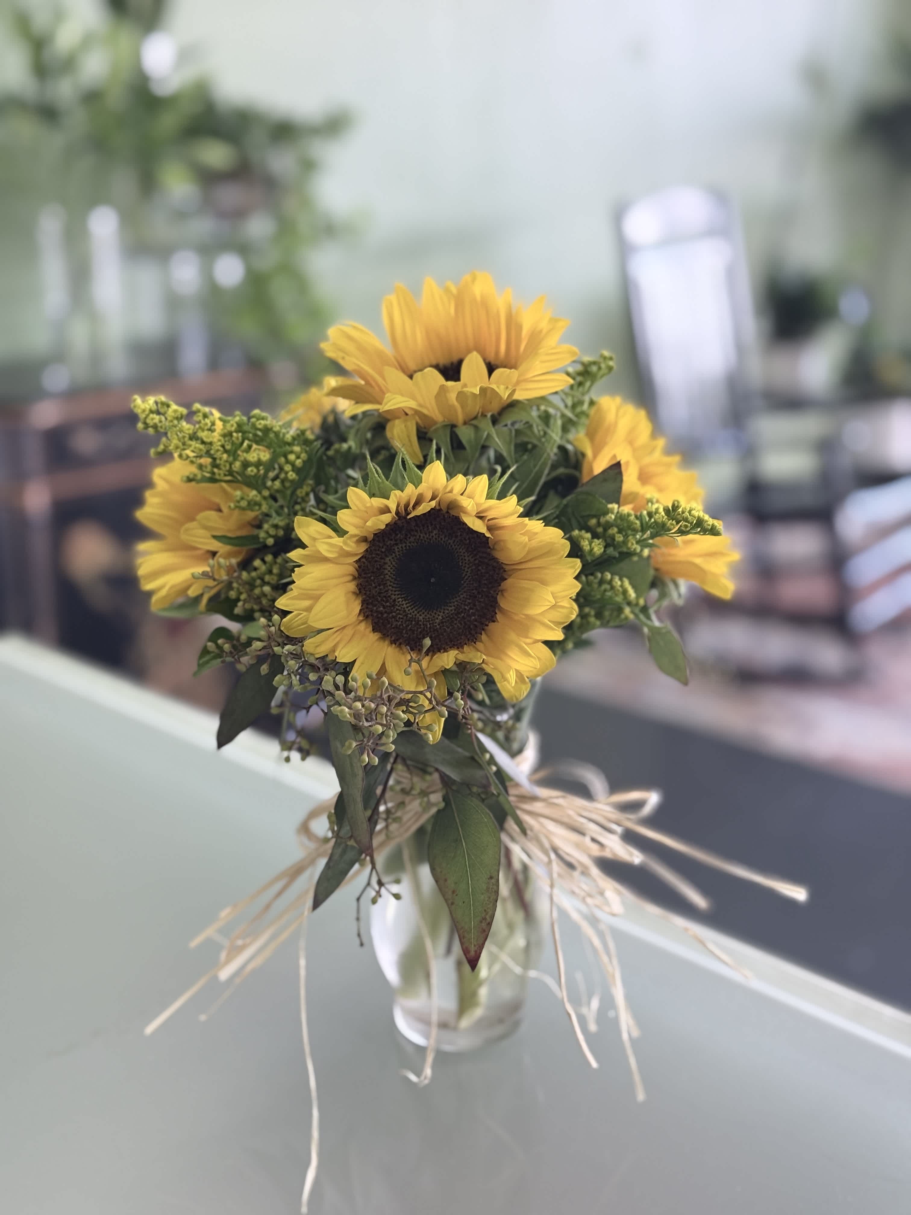 Sunflower bouquet in a clear glass vase with raffia tie