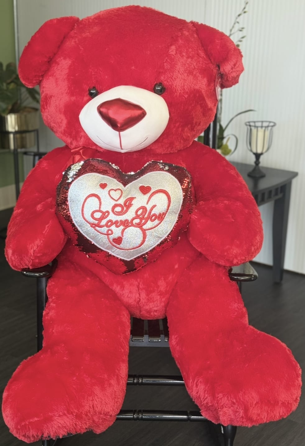 Large red teddy bear holding a heart pillow that says I Love You