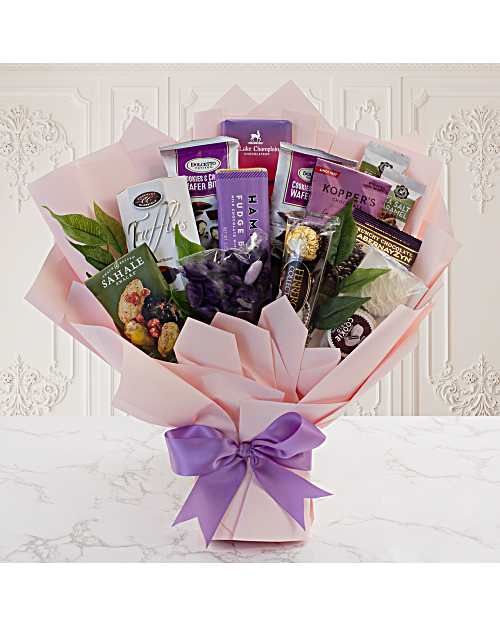 Gift bouquet of assorted chocolates and snacks wrapped in pink paper with a purple bow