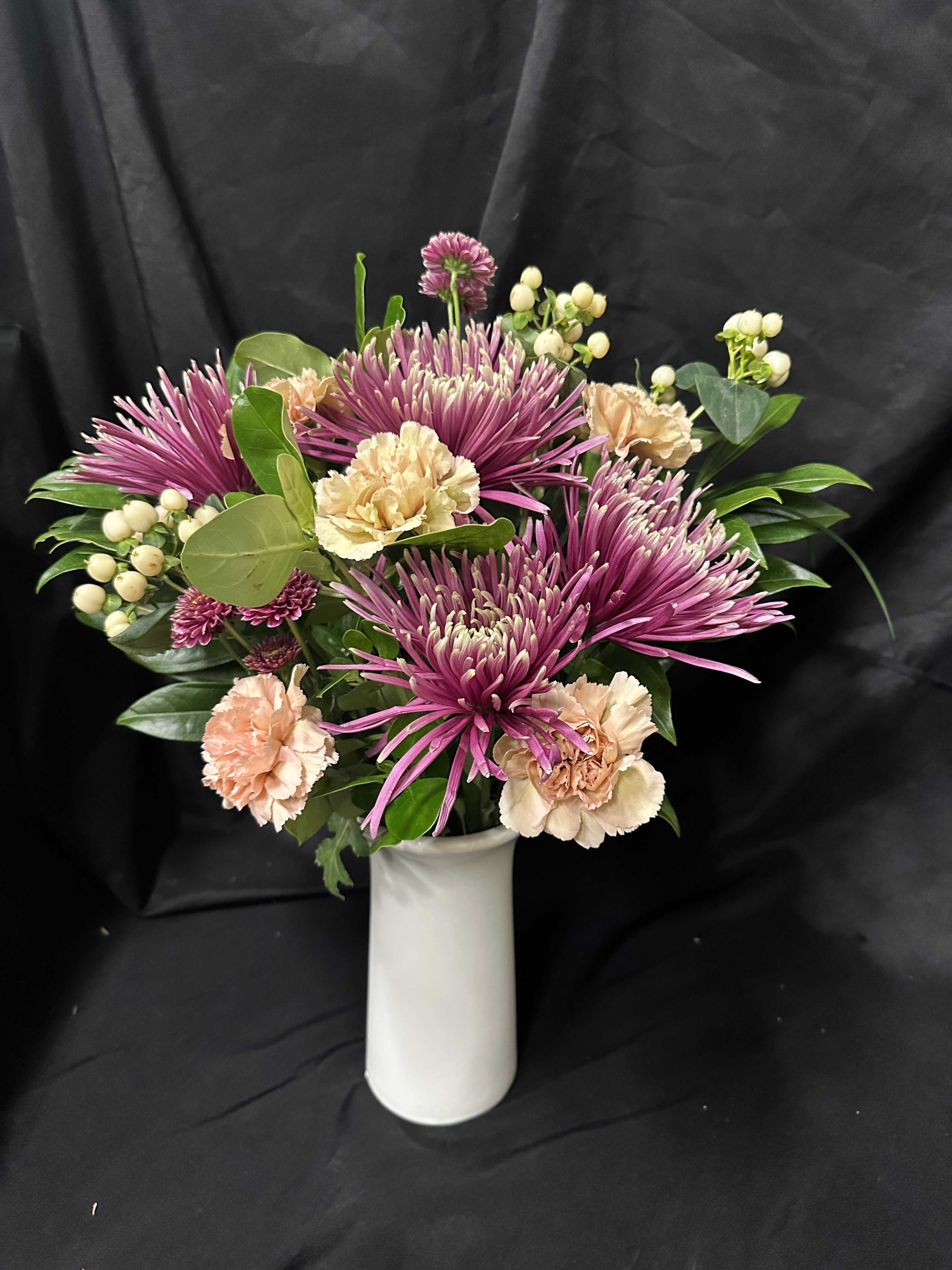 Pink chrysanthemums and peach carnations in a white vase