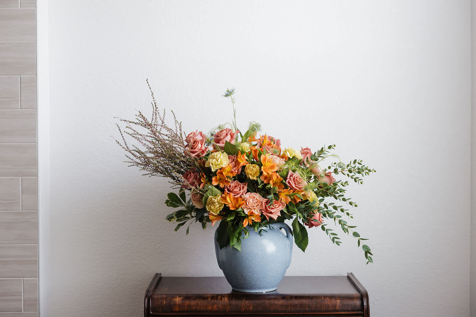 Mixed bouquet of pink and orange flowers in a blue vase