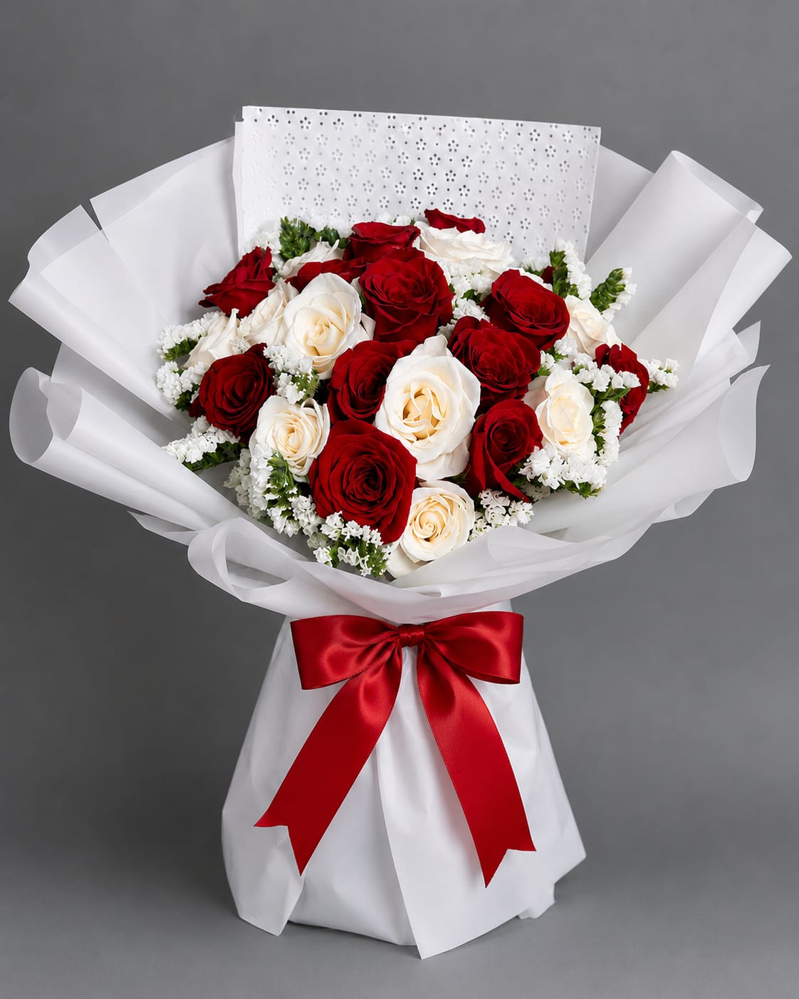 Bouquet of red and white roses wrapped in white paper with a red ribbon