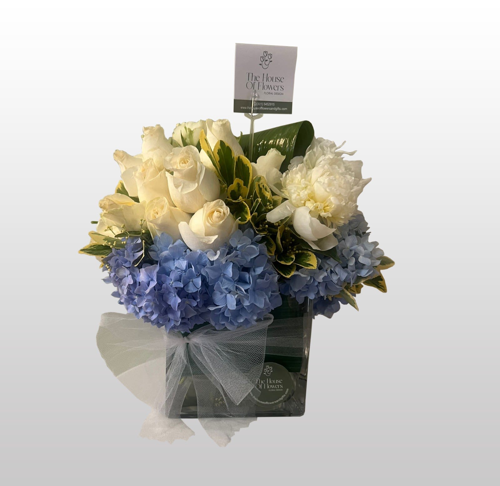 Bouquet of white roses and blue hydrangeas in a gift box with a sheer bow