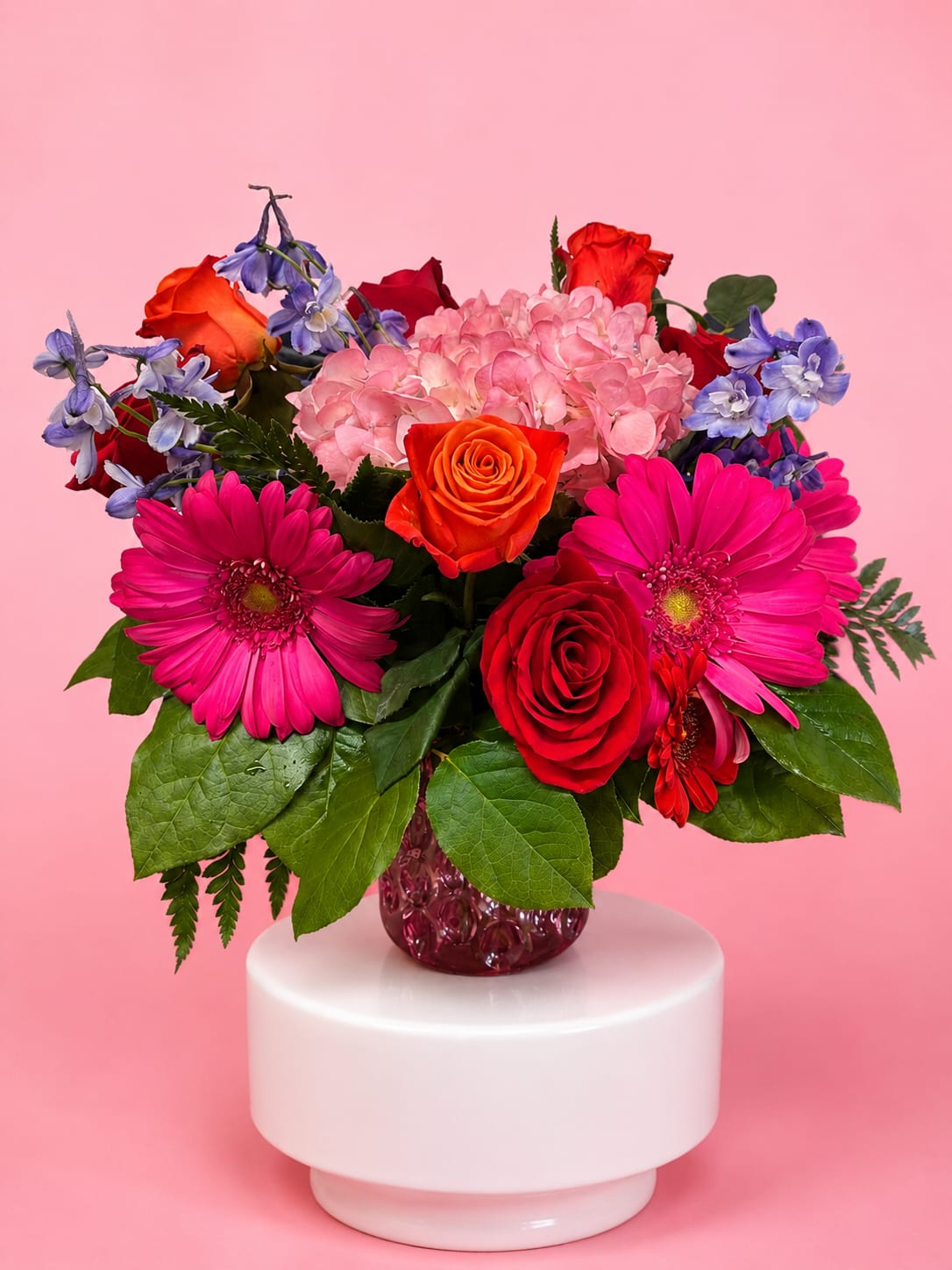 Mixed bouquet of roses, hydrangea, and gerbera daisies in a glass vase