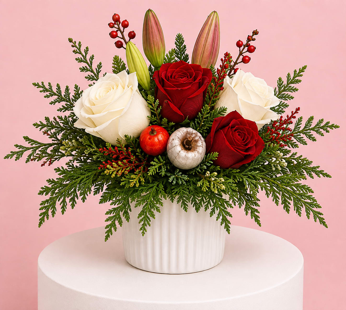 Red and white roses in a white vase with evergreen accents and berries