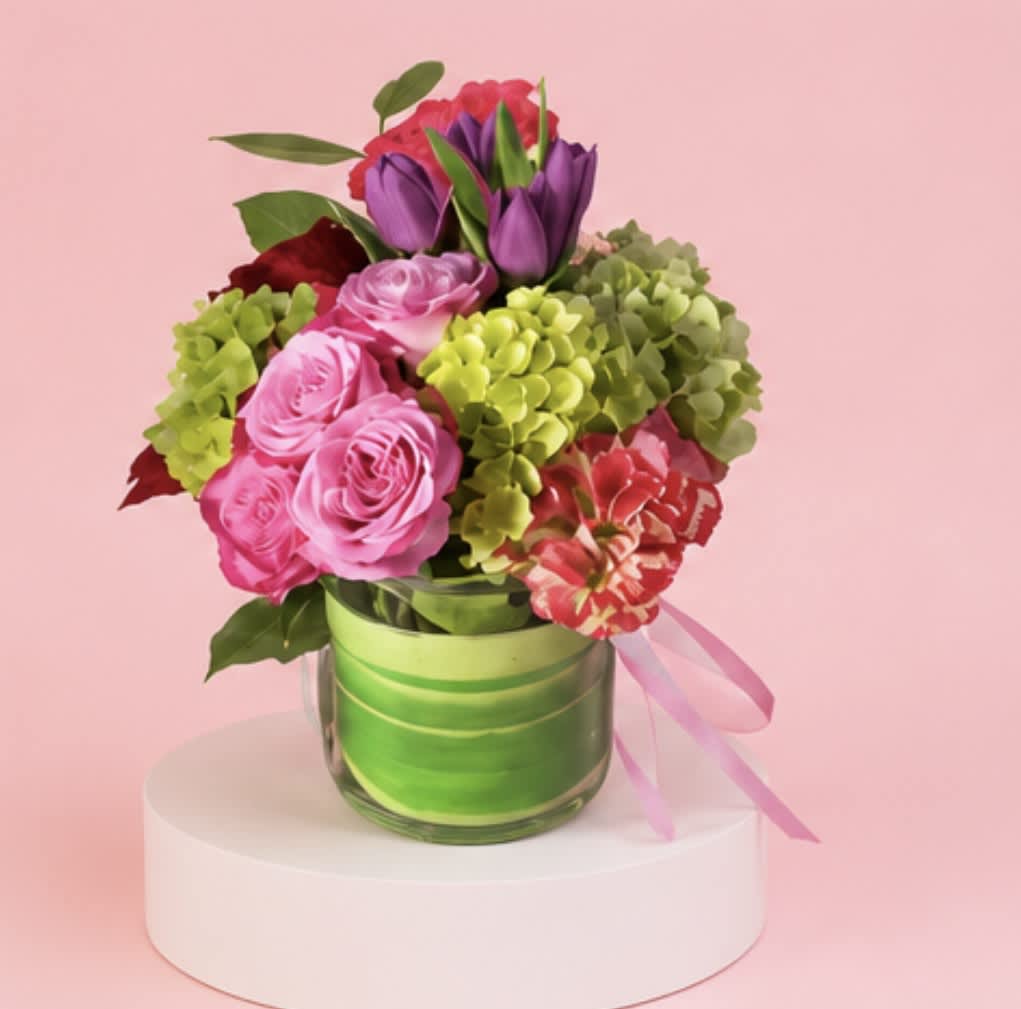 Pink and purple bouquet in a glass vase with a pink ribbon