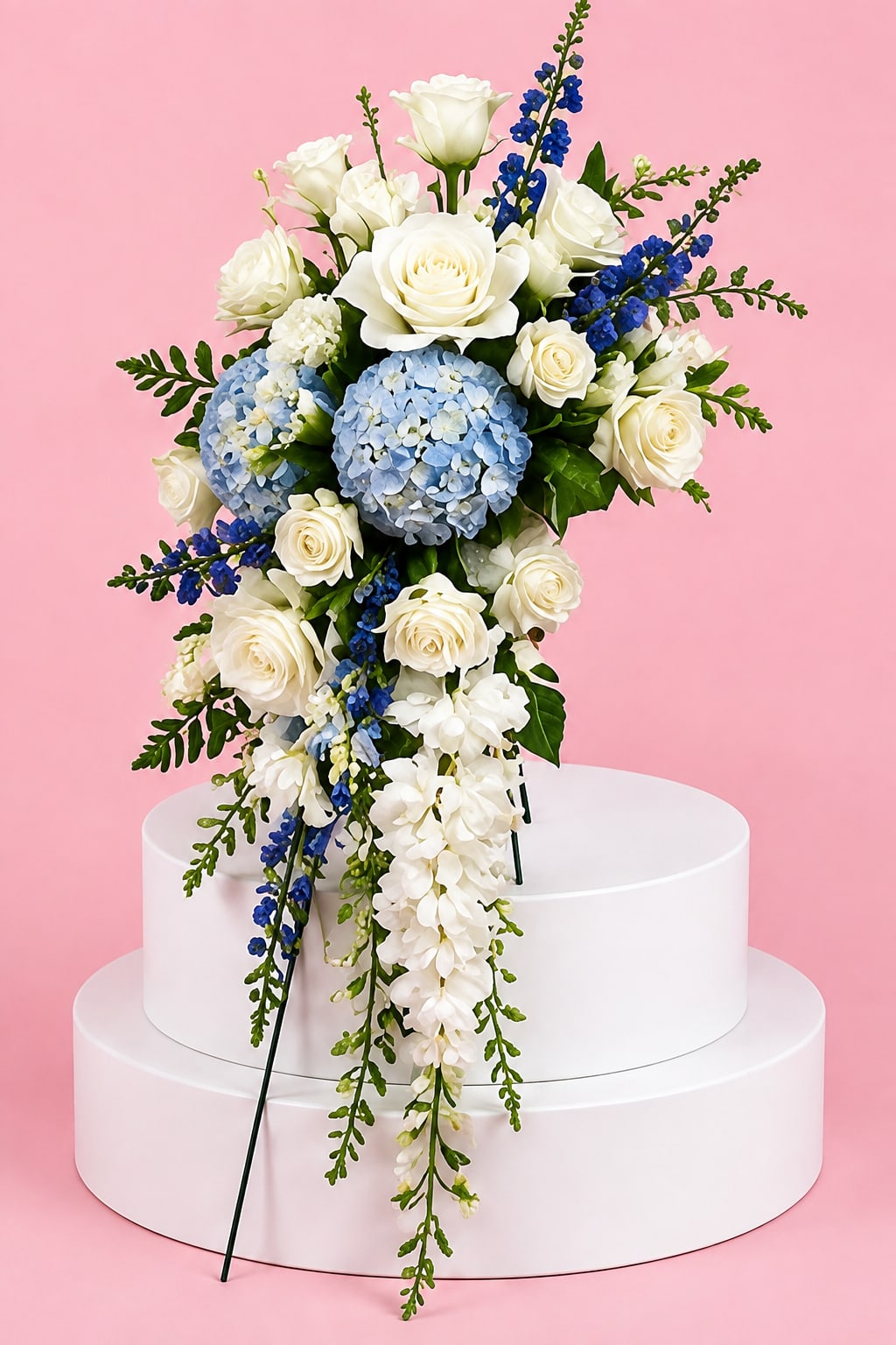 White roses and blue hydrangeas in a cascading bouquet on a pedestal