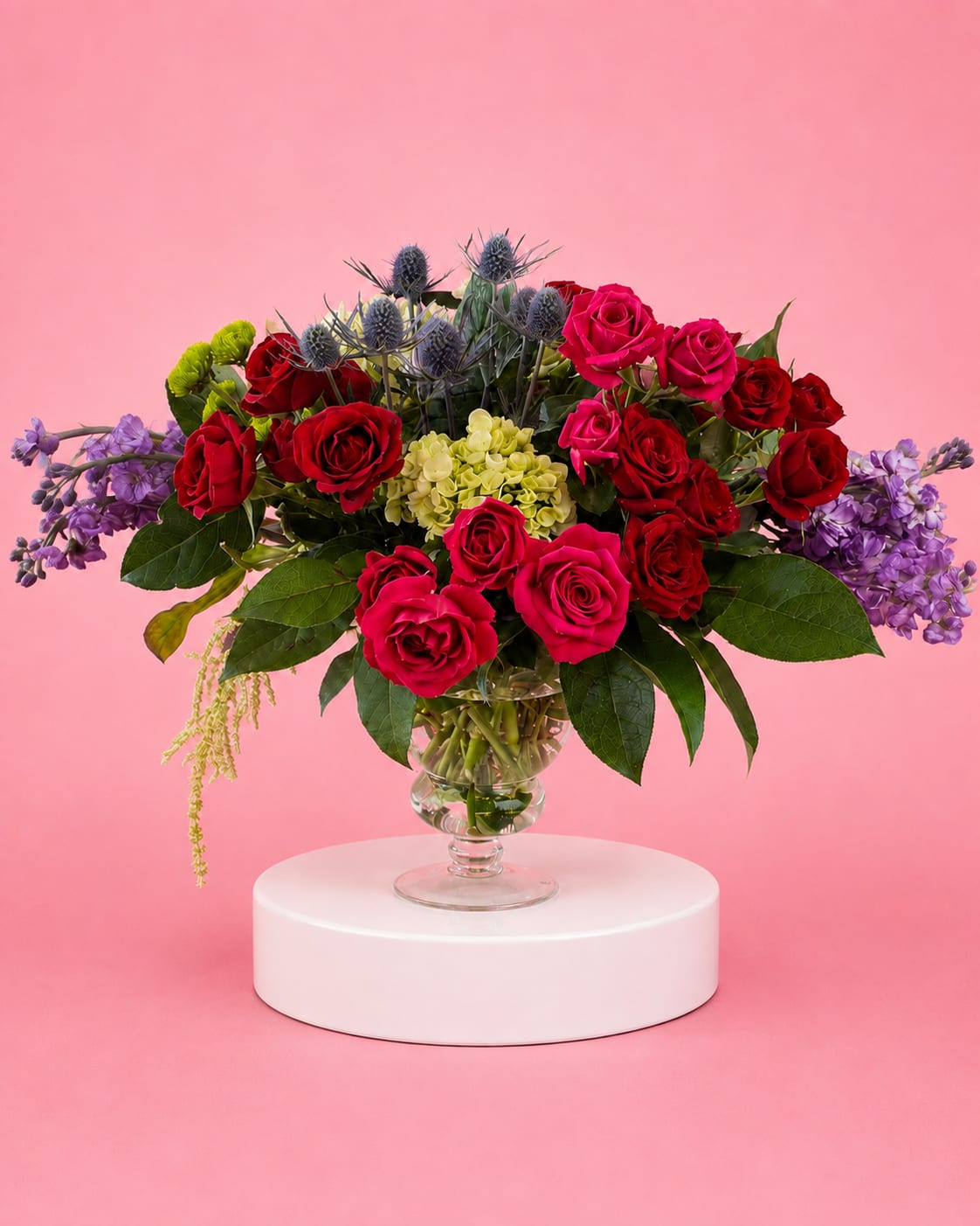 Bouquet of red and pink roses with purple flowers in a glass vase