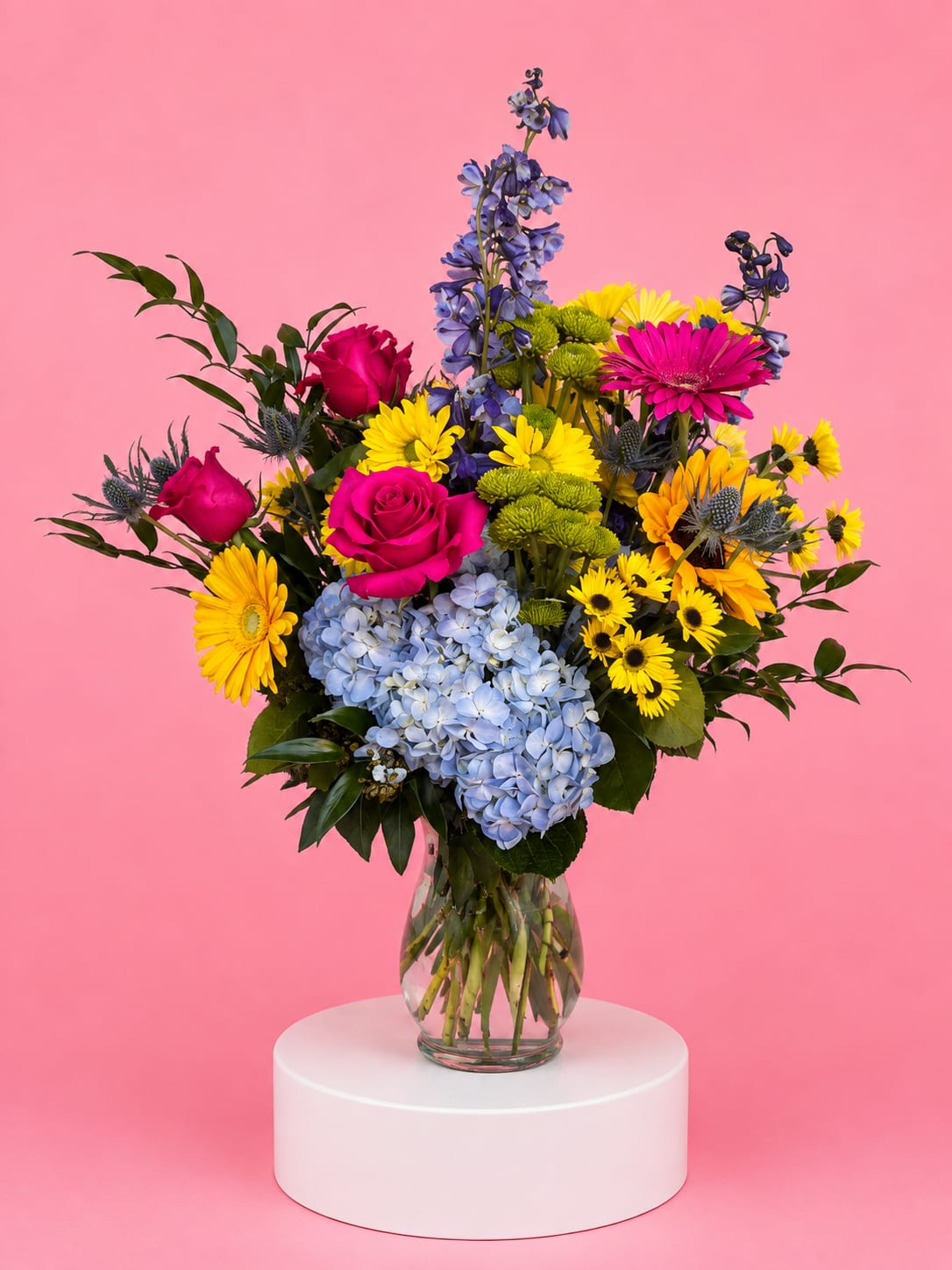 Colorful bouquet of roses, hydrangeas, and daisies in a glass vase