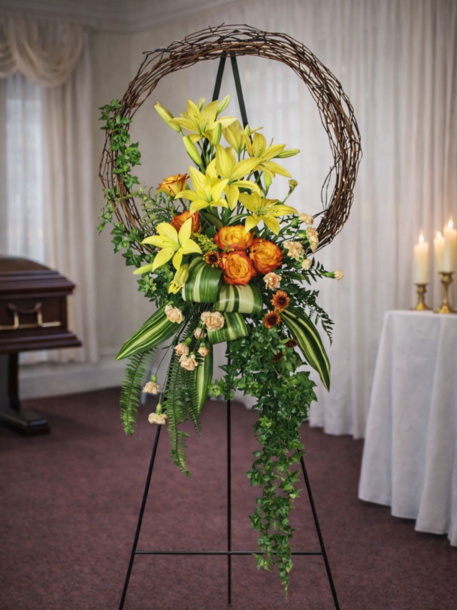 Standing floral spray with yellow lilies and orange roses on an easel