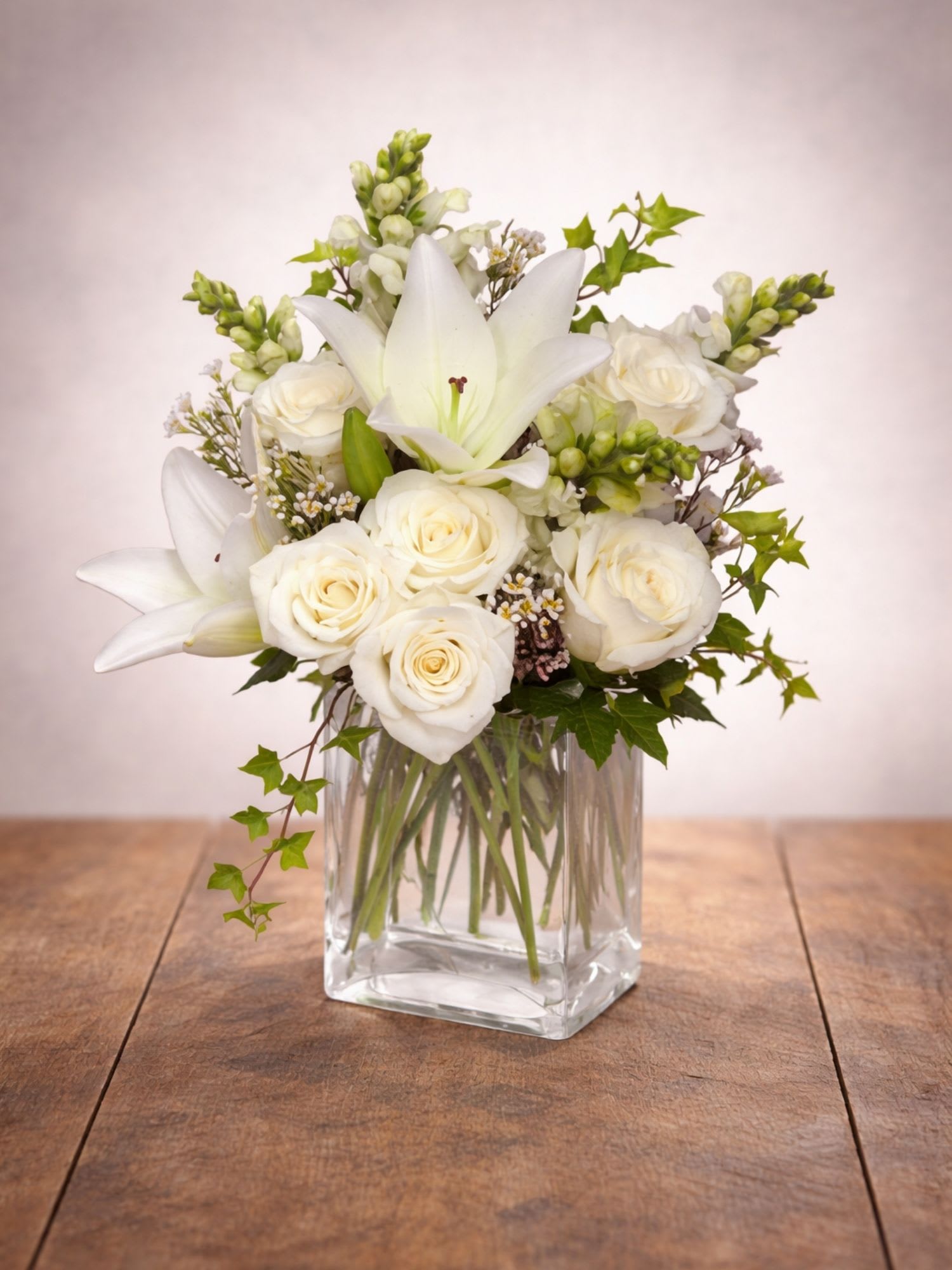 White roses and lilies arranged in a clear glass vase