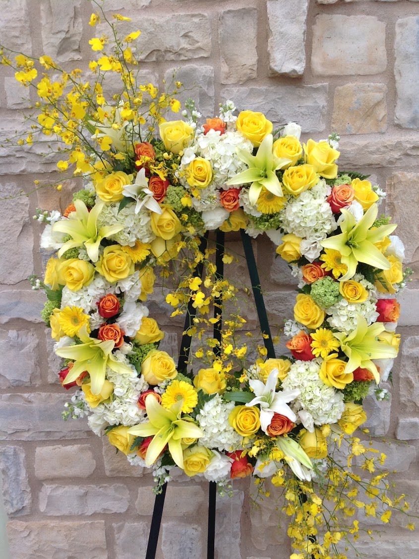 Yellow and white floral wreath on a black stand