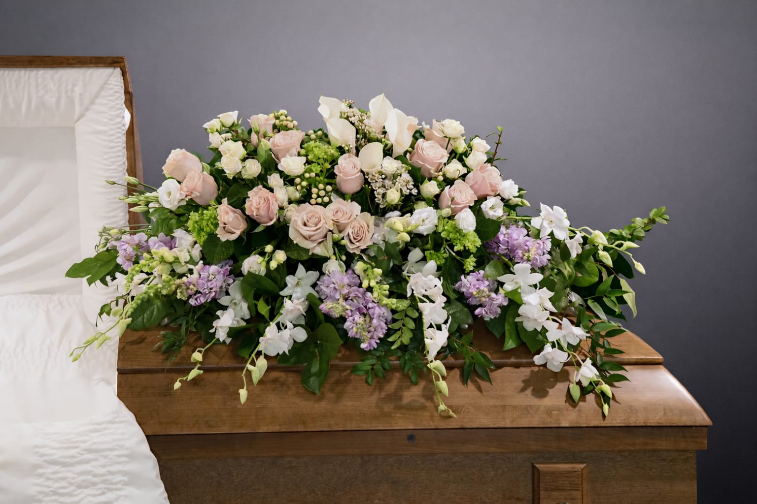 Pastel floral casket spray with roses, lilies, and orchids