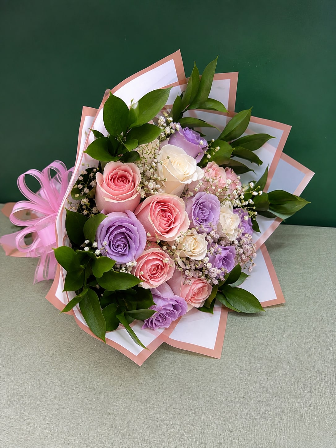 Bouquet of pink, lavender, and white roses with baby’s breath and ribbon wrap