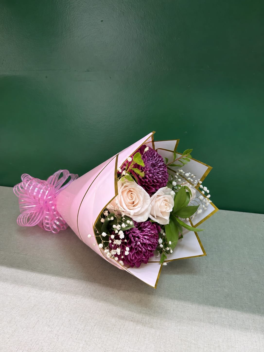 Pink-wrapped bouquet with white roses and purple chrysanthemums