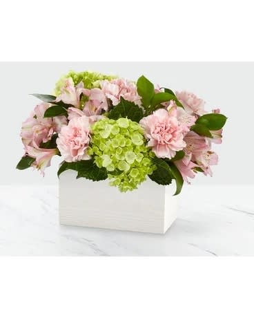 Pink flowers and green hydrangeas arranged in a white box