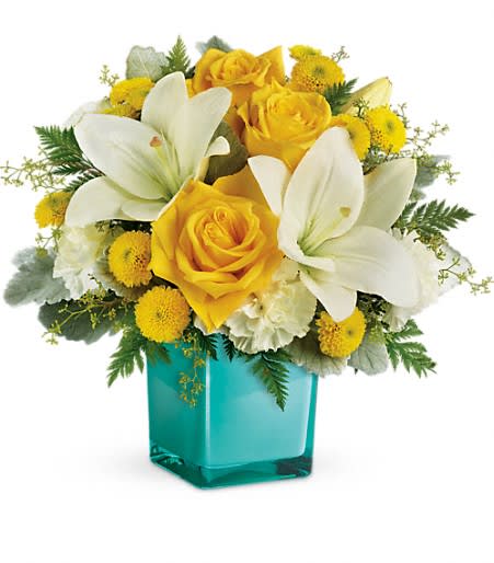 Yellow roses and white lilies in a turquoise vase