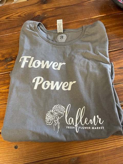 Folded gray T-shirt with white flower-themed text and graphic