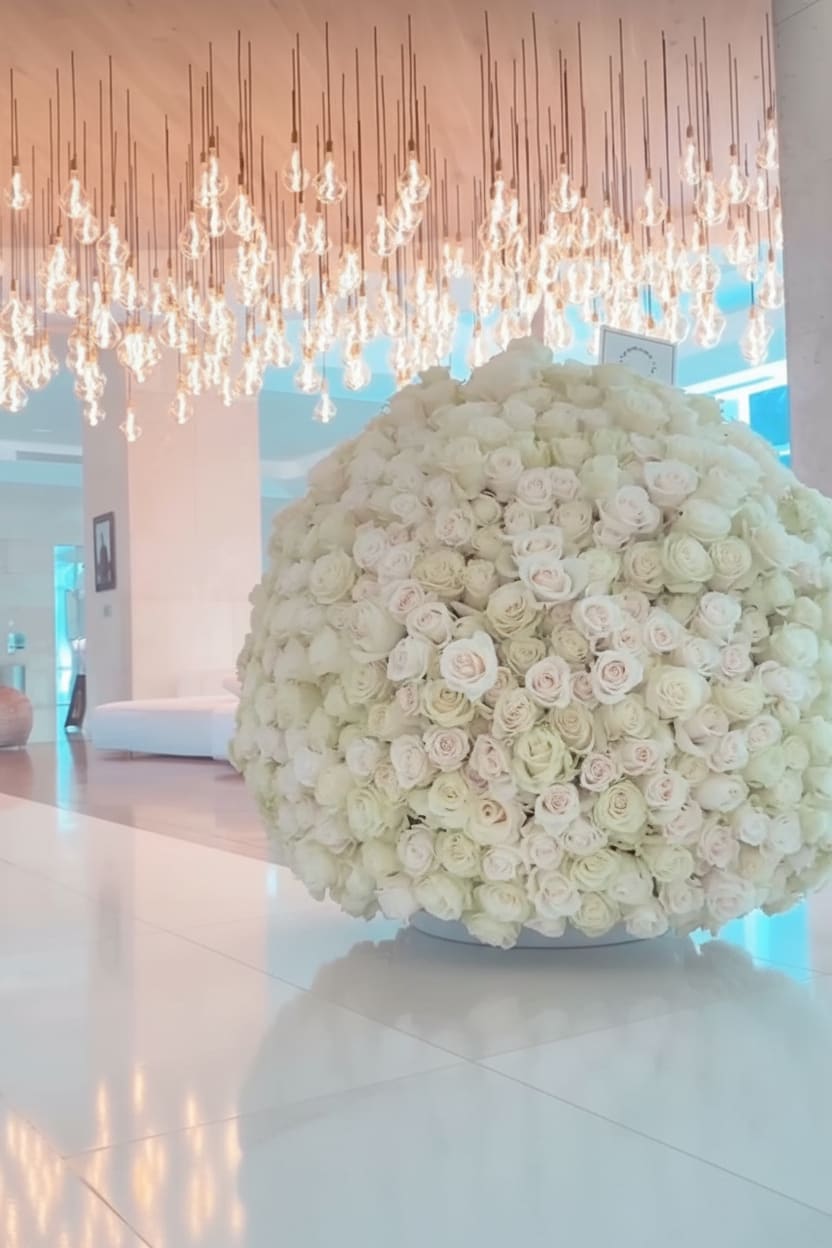 Large spherical arrangement of ivory and blush roses on a low white base in a modern lobby