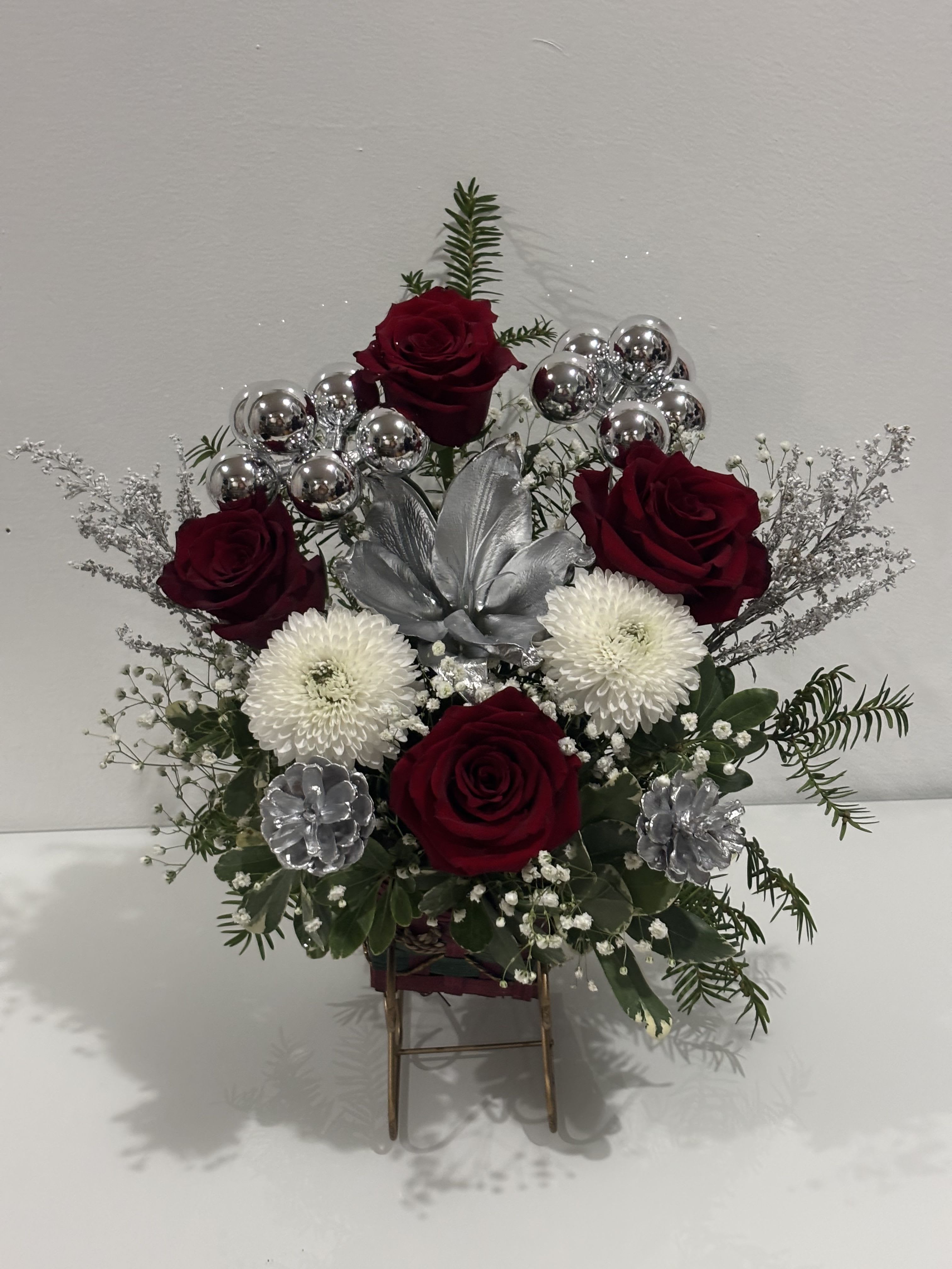 Arrangement of red roses and white mums with silver accents in a stand