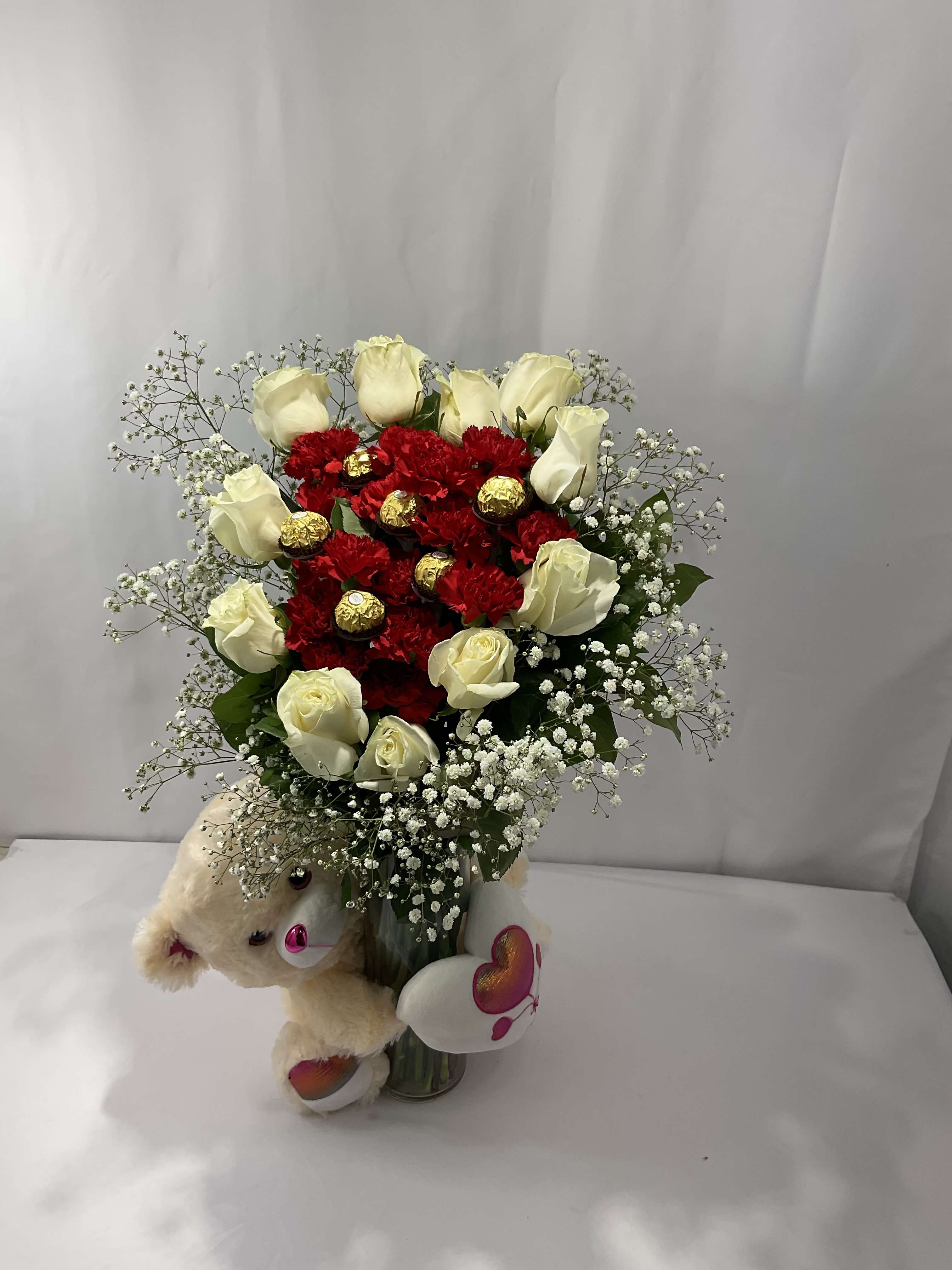 Bouquet of red and white roses with a teddy bear and heart decorations