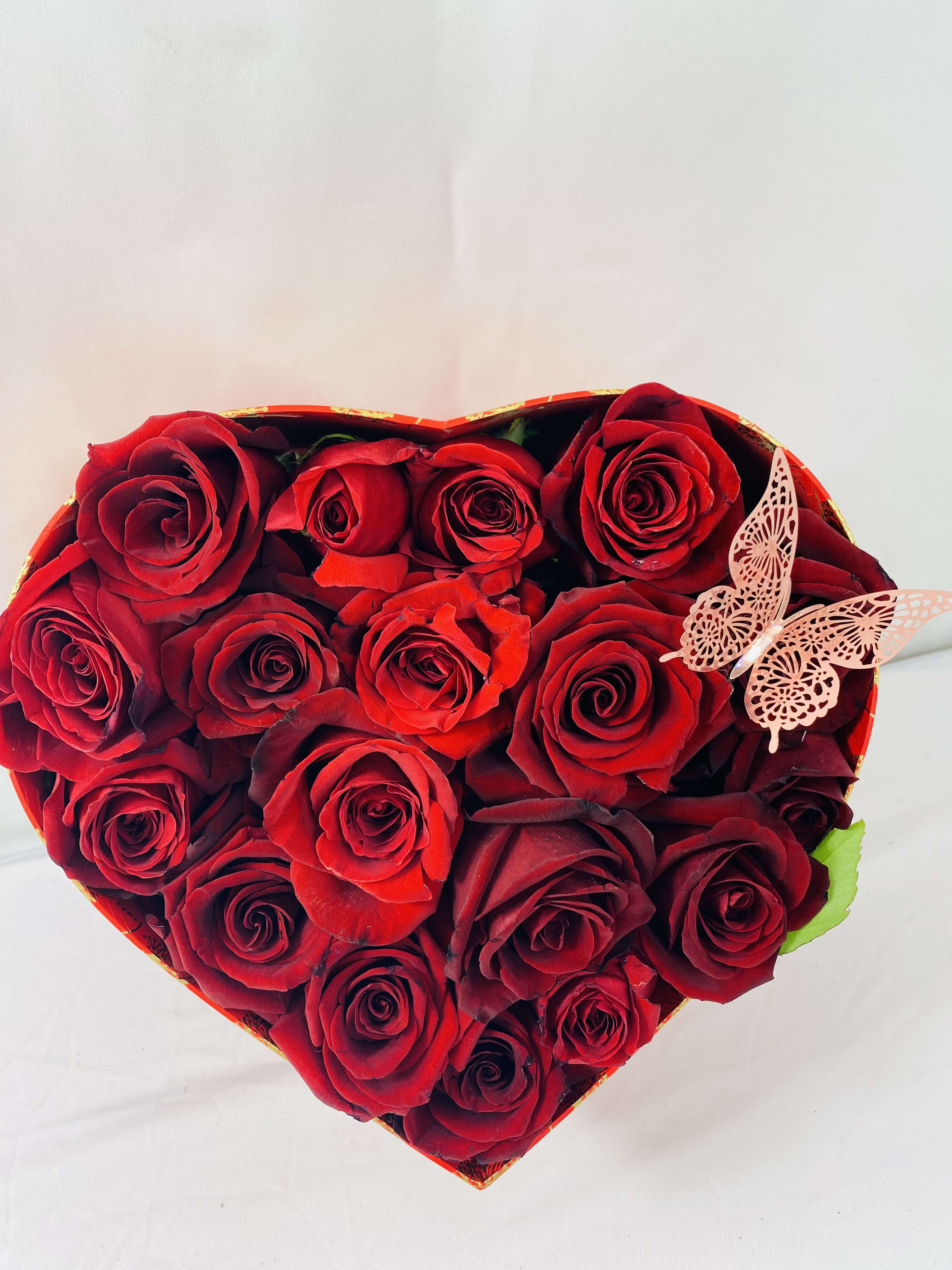 Heart-shaped box of red roses with a butterfly decoration