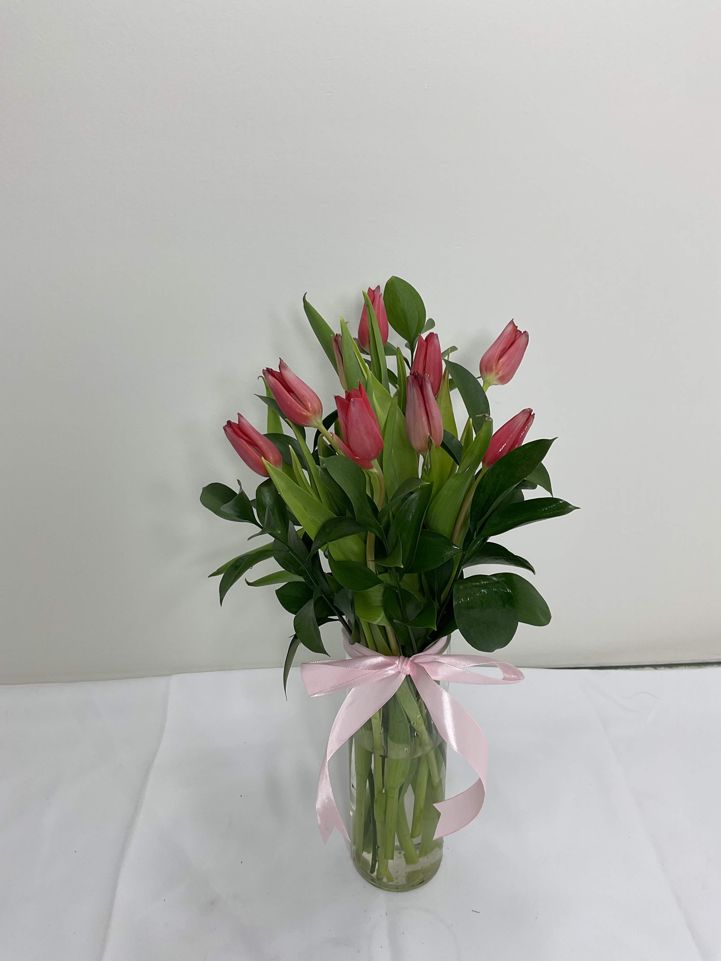 Pink tulips in a clear glass vase tied with a pink ribbon
