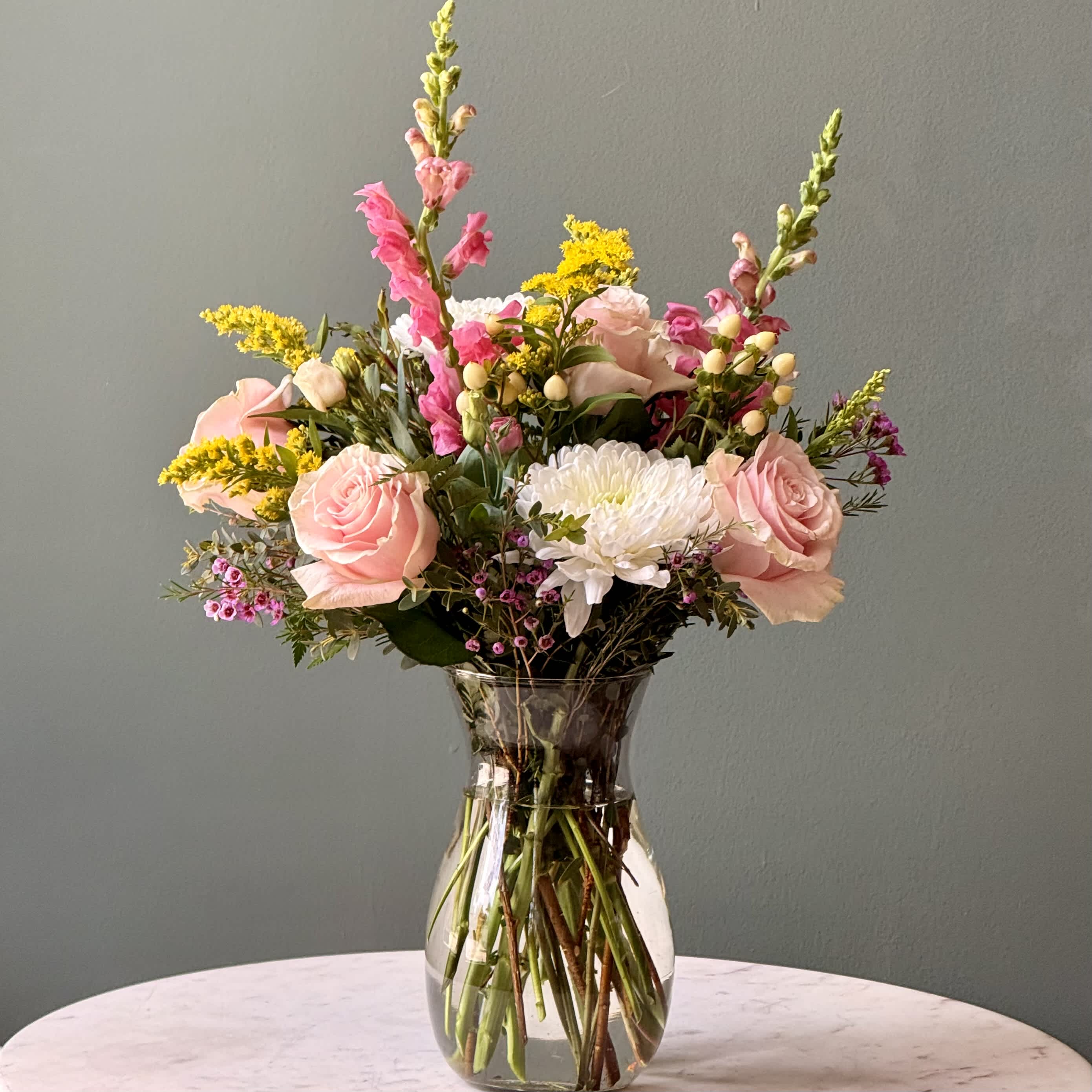 Pink roses and white blooms arranged in a clear glass vase