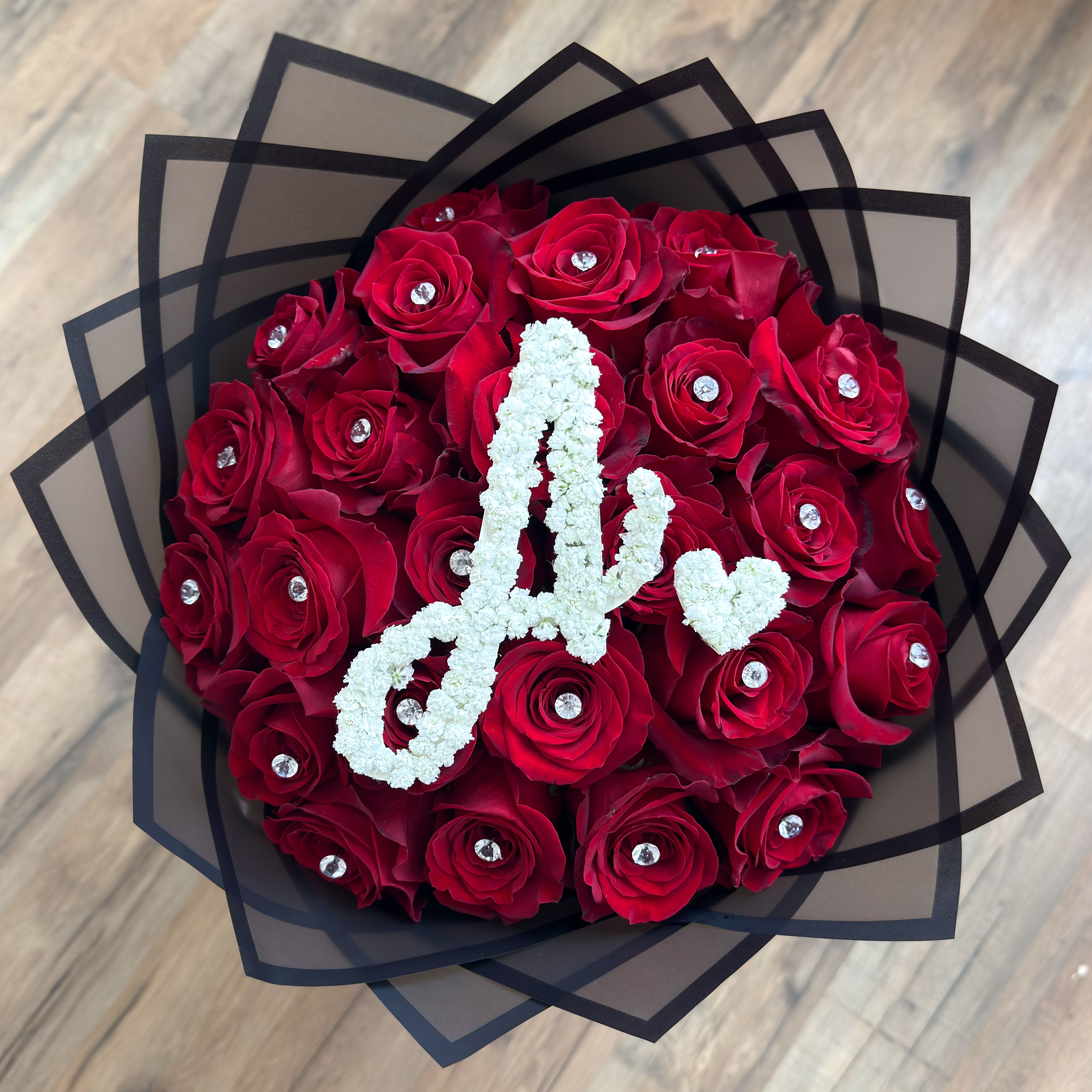 Initial Rose Bouquet - A stunning bouquet of 24 red roses beautifully arranged with sparkling gems and a custom white floral initial in the center. Perfect for birthdays, anniversaries, or any special surprise.   Please leave a note at checkout with the initial you’d like, or call us after placing your order to confirm your letter.