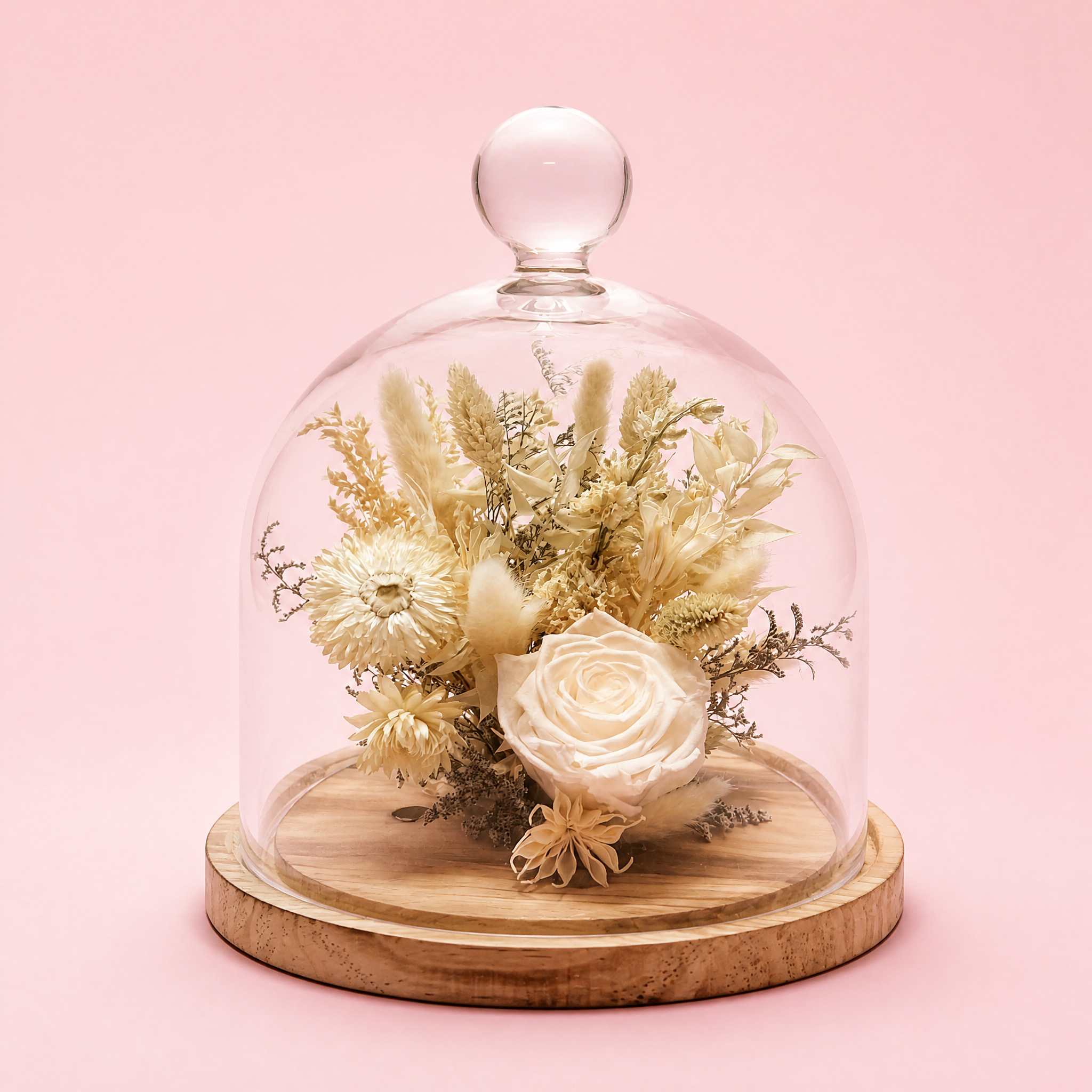 Dried floral arrangement under a glass dome on a wooden base