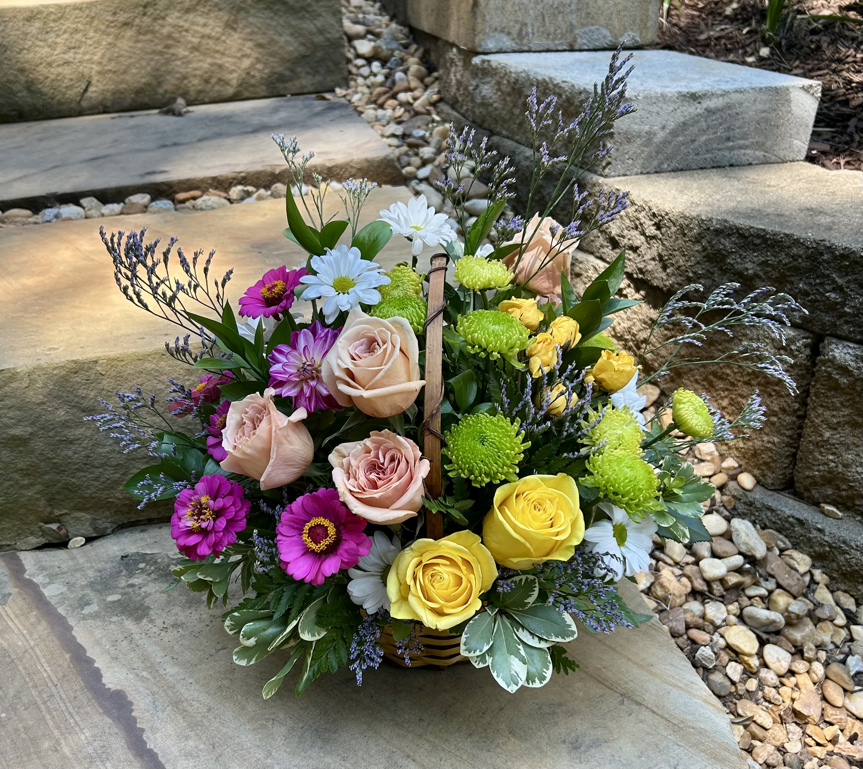 Mixed bouquet with roses, daisies, and bright mums in a basket