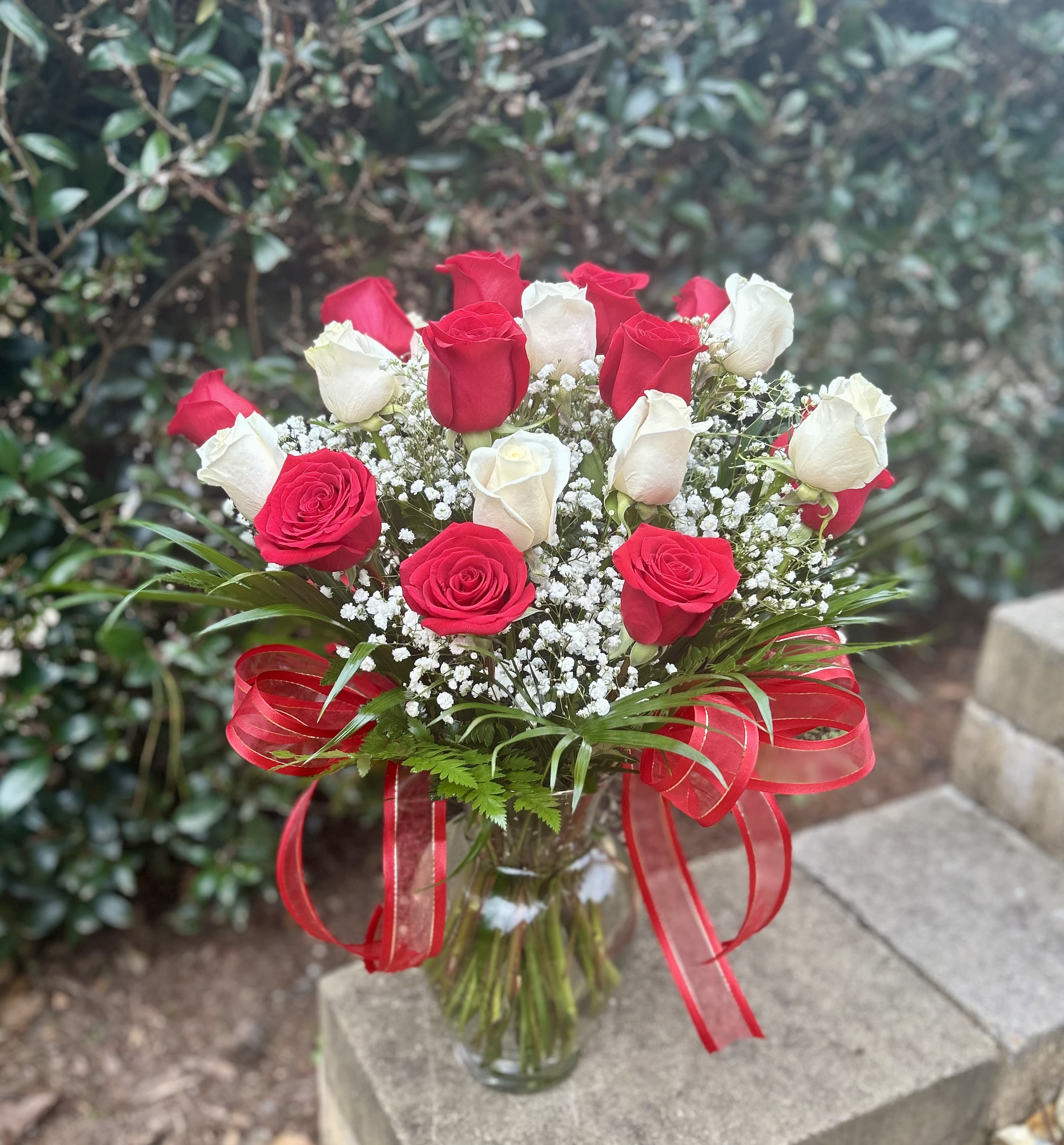 Bouquet of red and white roses in a glass vase with a red ribbon